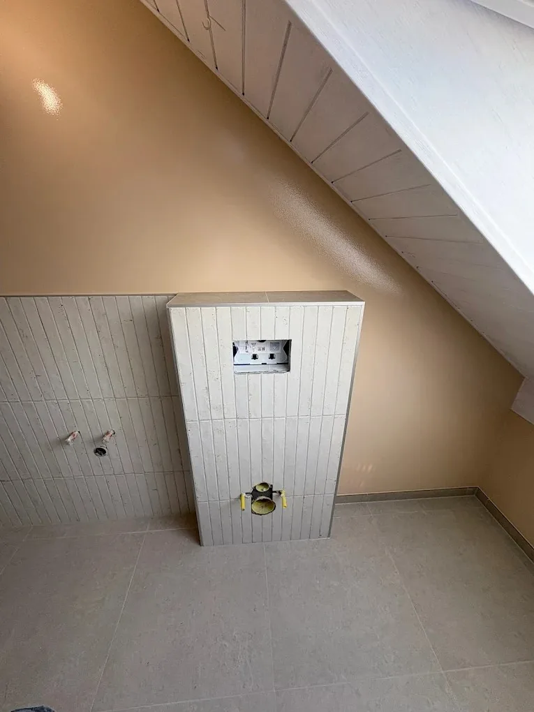 Habillage carrelé du WC suspendu dans une salle de bain sous combles à Trélex