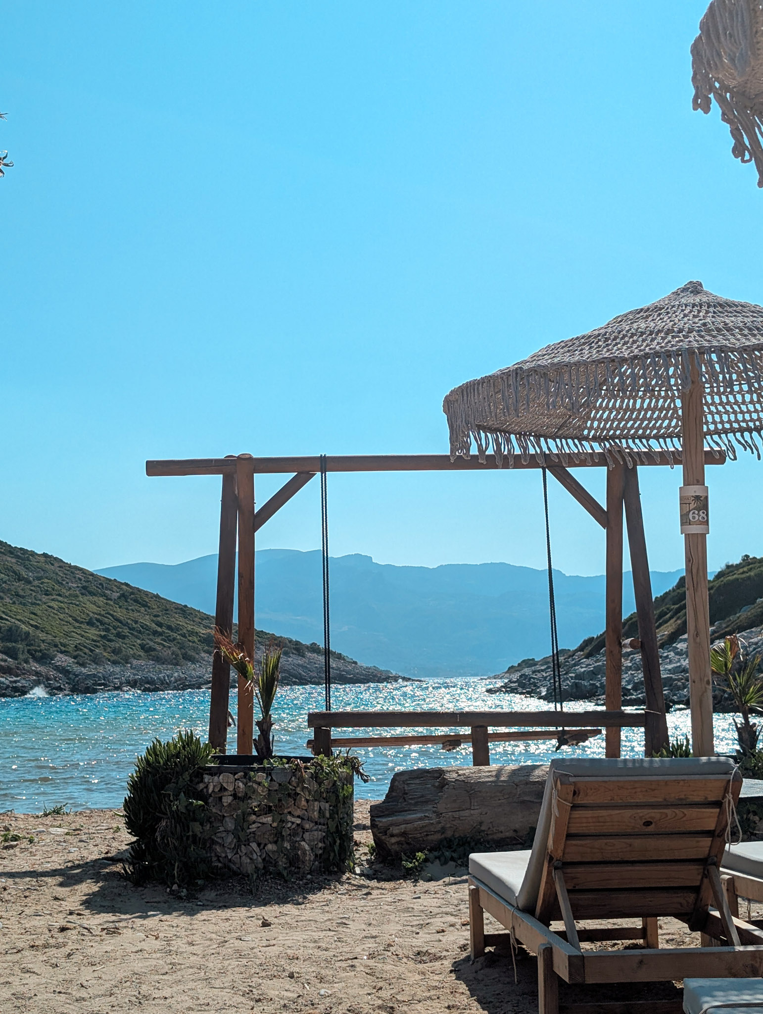 A swing and sunbeds on a quiet beach on Samos