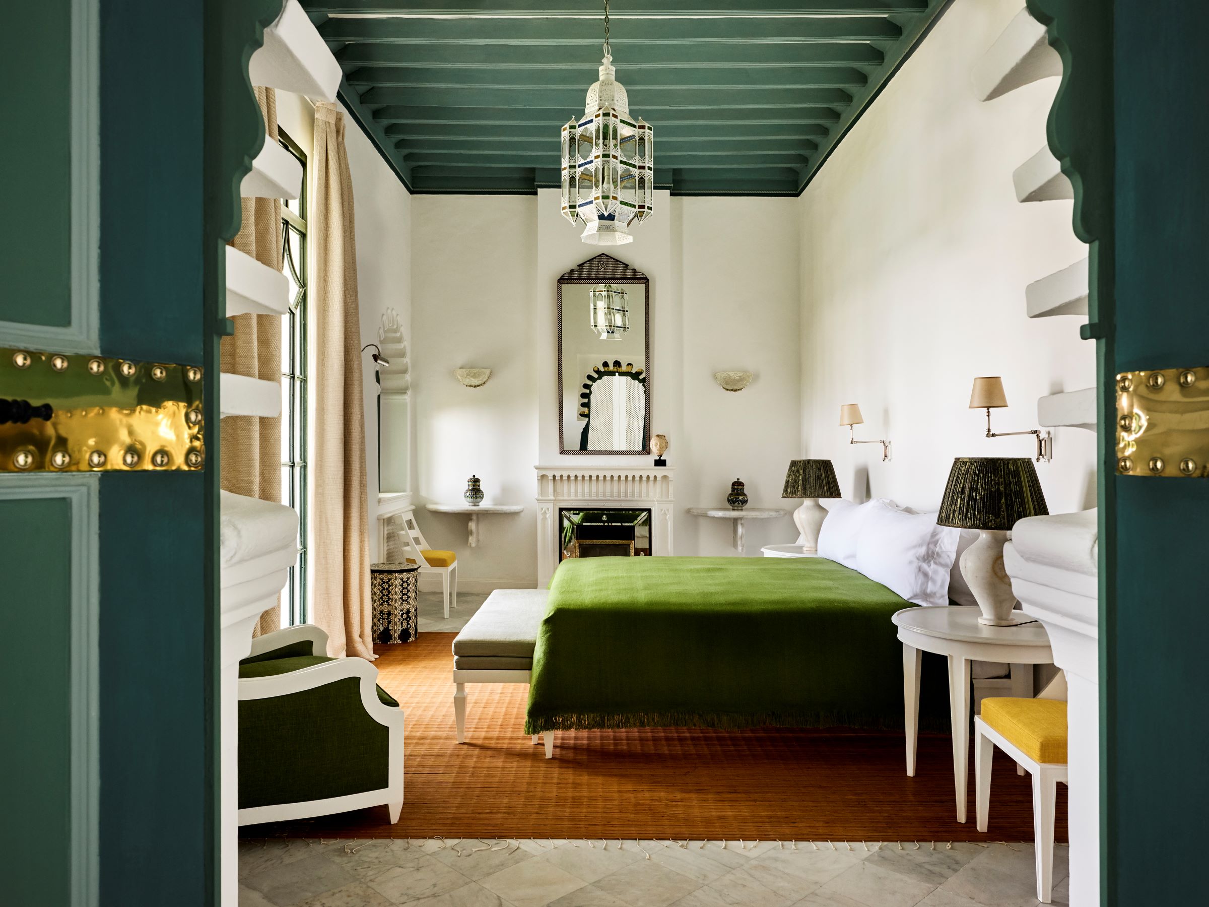 Suite with a green ceiling, green bedspread and arched doorway at Villa Mabrouka