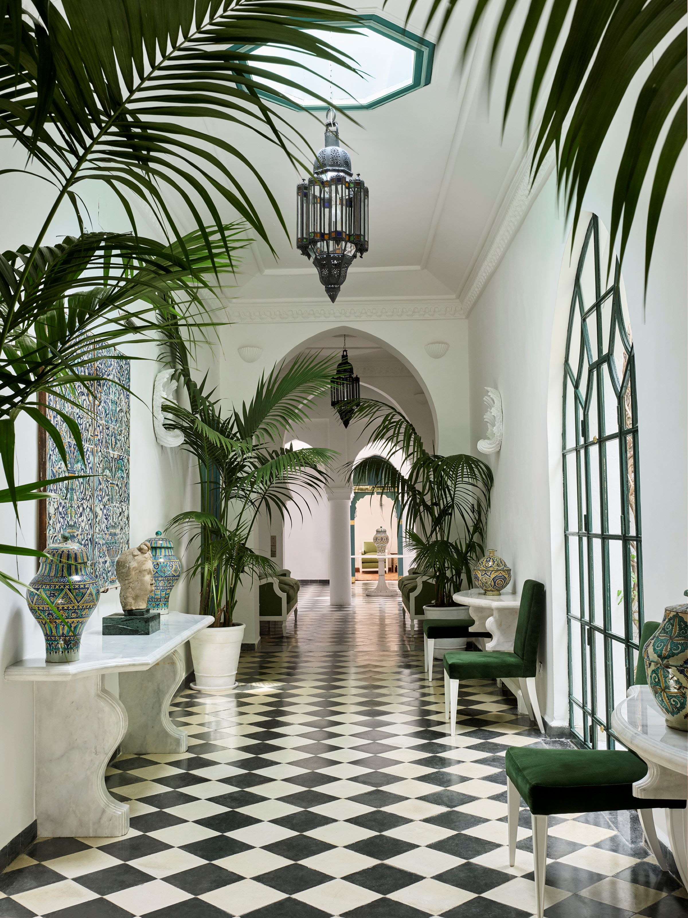 White veranda with a black and white chequered floor, lanterns and palms at Villa Mabrouka