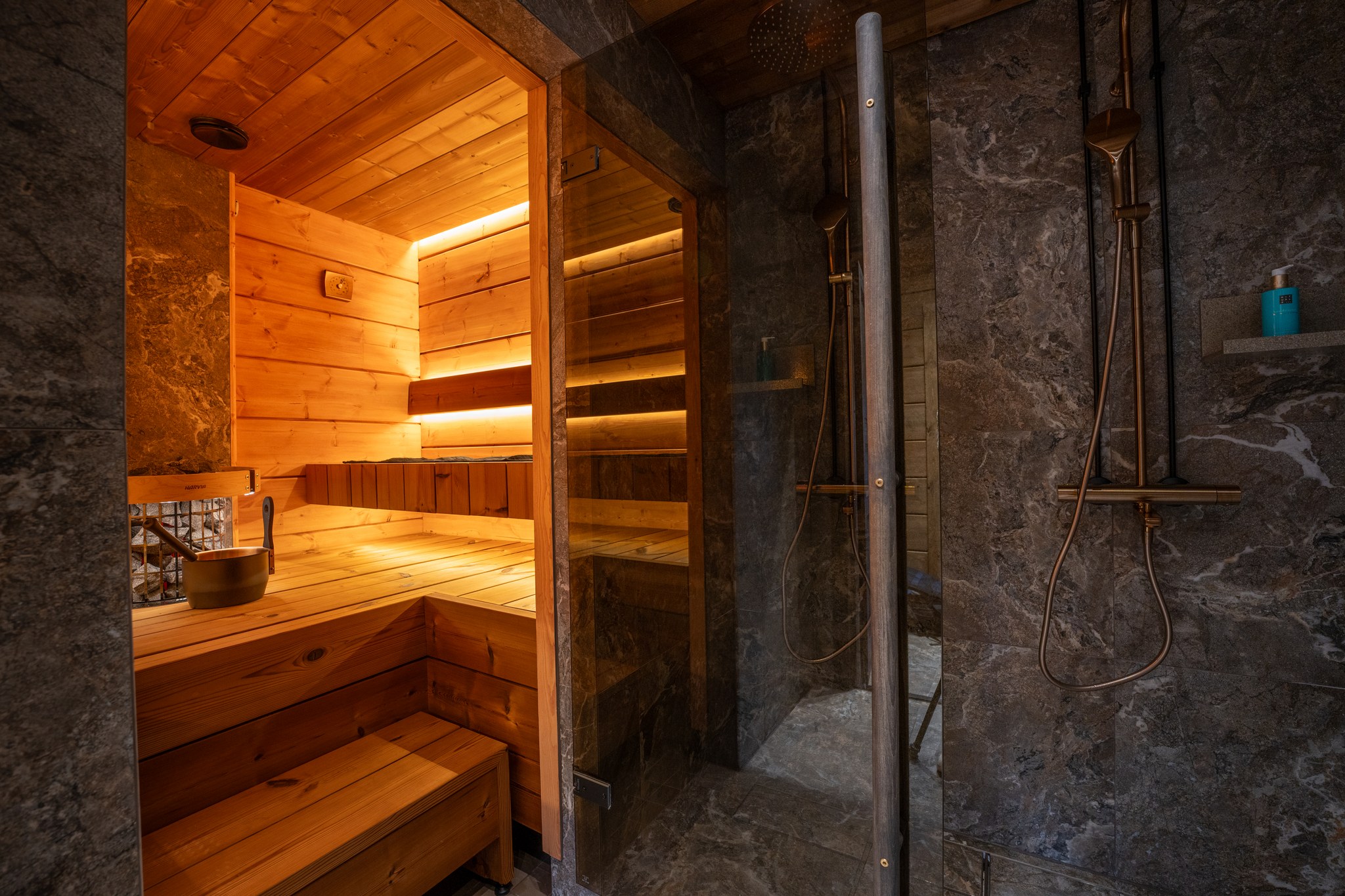 Wooden sauna next to a stone-clad shower at Levin Iglut