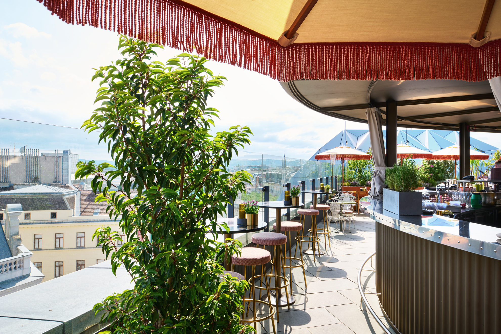 Rooftop bar at Hotel MOTTO with a fringed parasol and views over the rooftops of Vienna