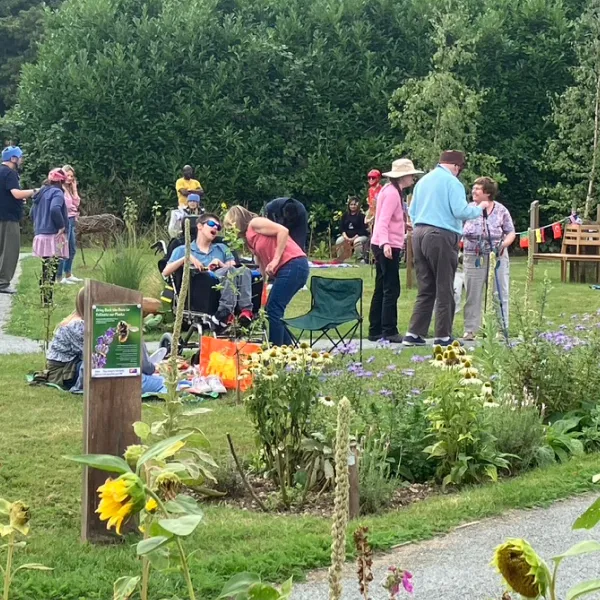 Group of people socialising and relaxing in a garden with flowers and greenery.