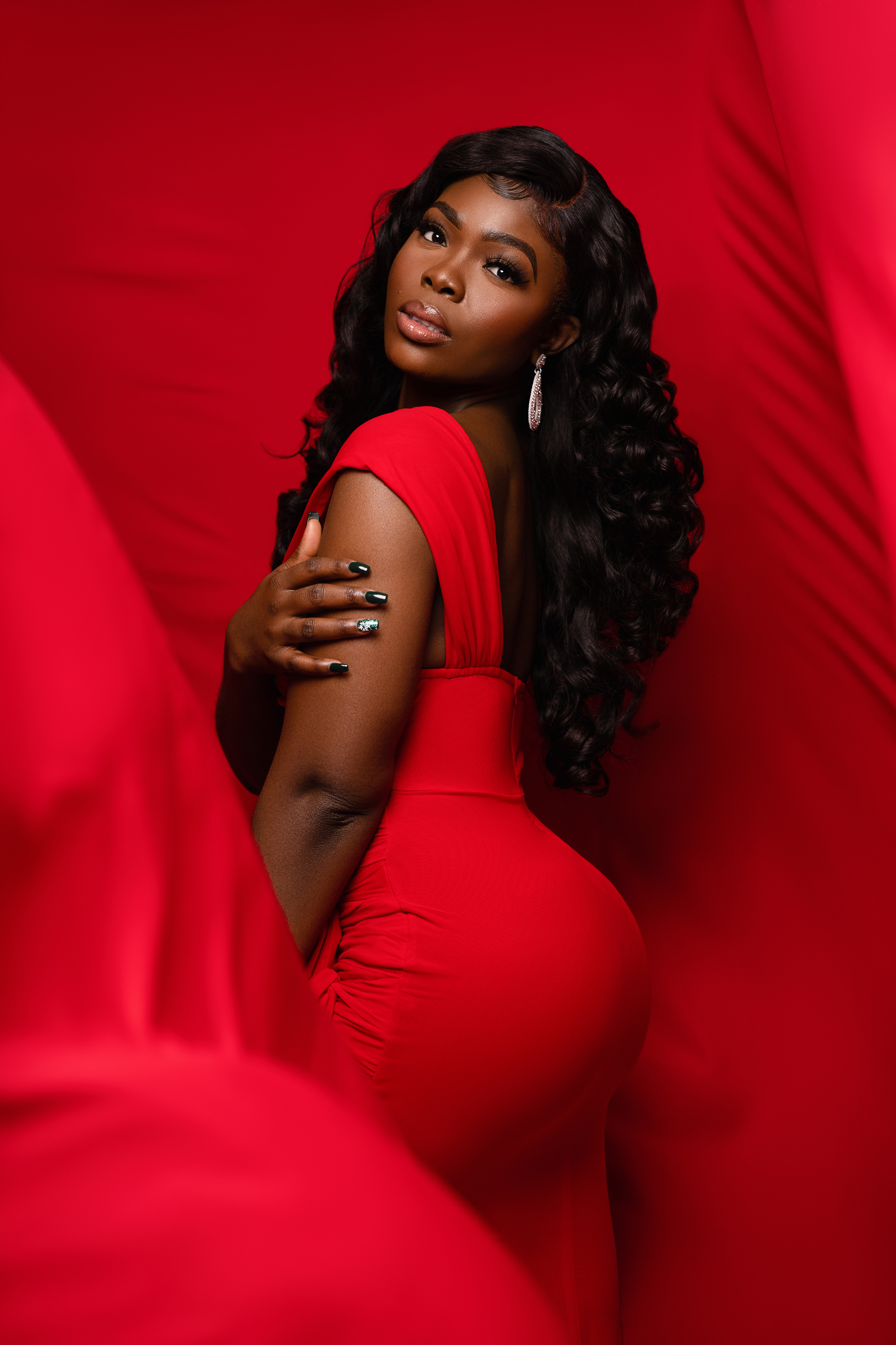 Beauty portrait of a Black woman posing in a red dress against a red backdrop