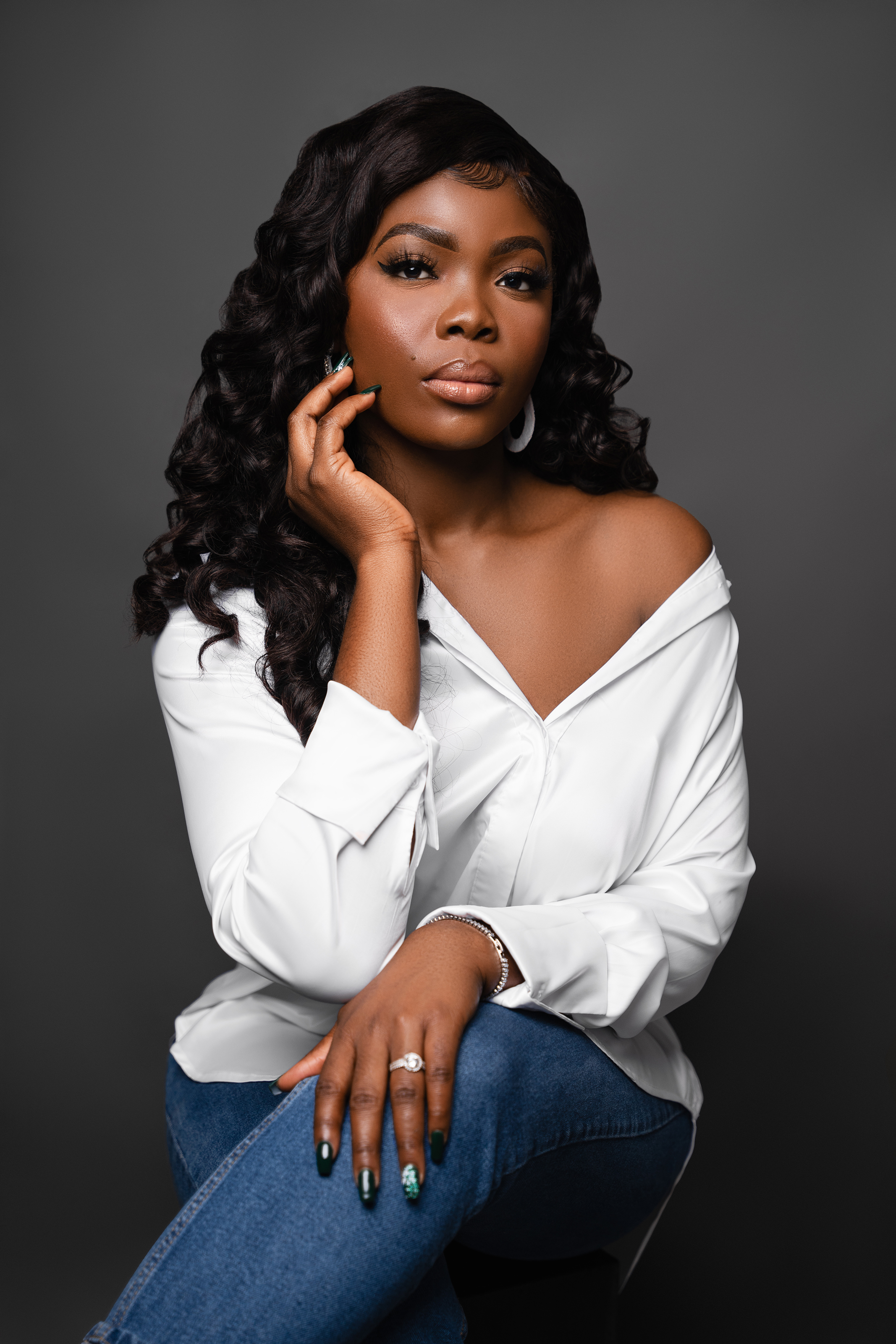 Studio portrait of a Black woman in a white shirt against a dark grey background