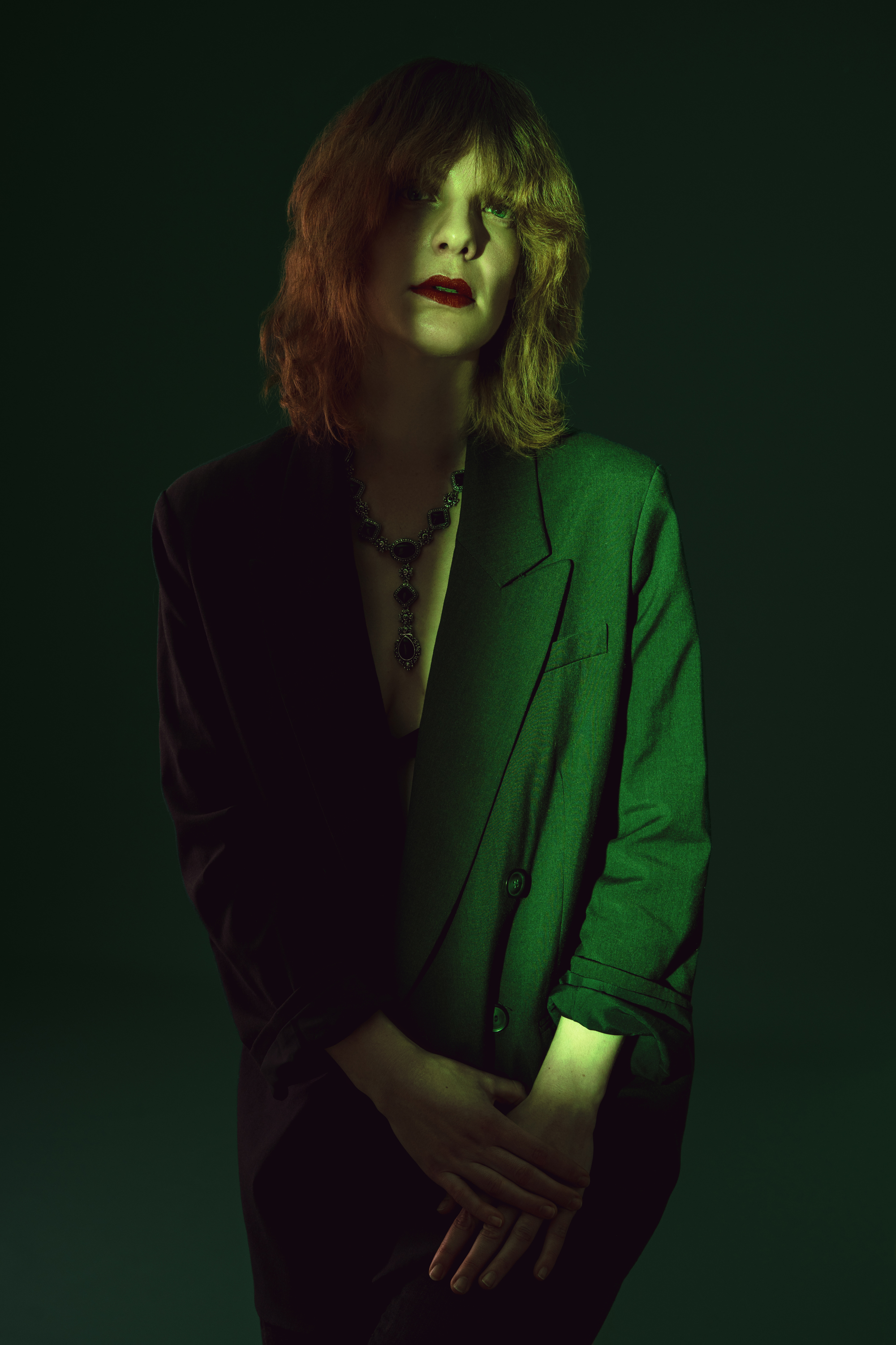 Editorial studio portrait of a woman in a dark blazer illuminated by dramatic green light