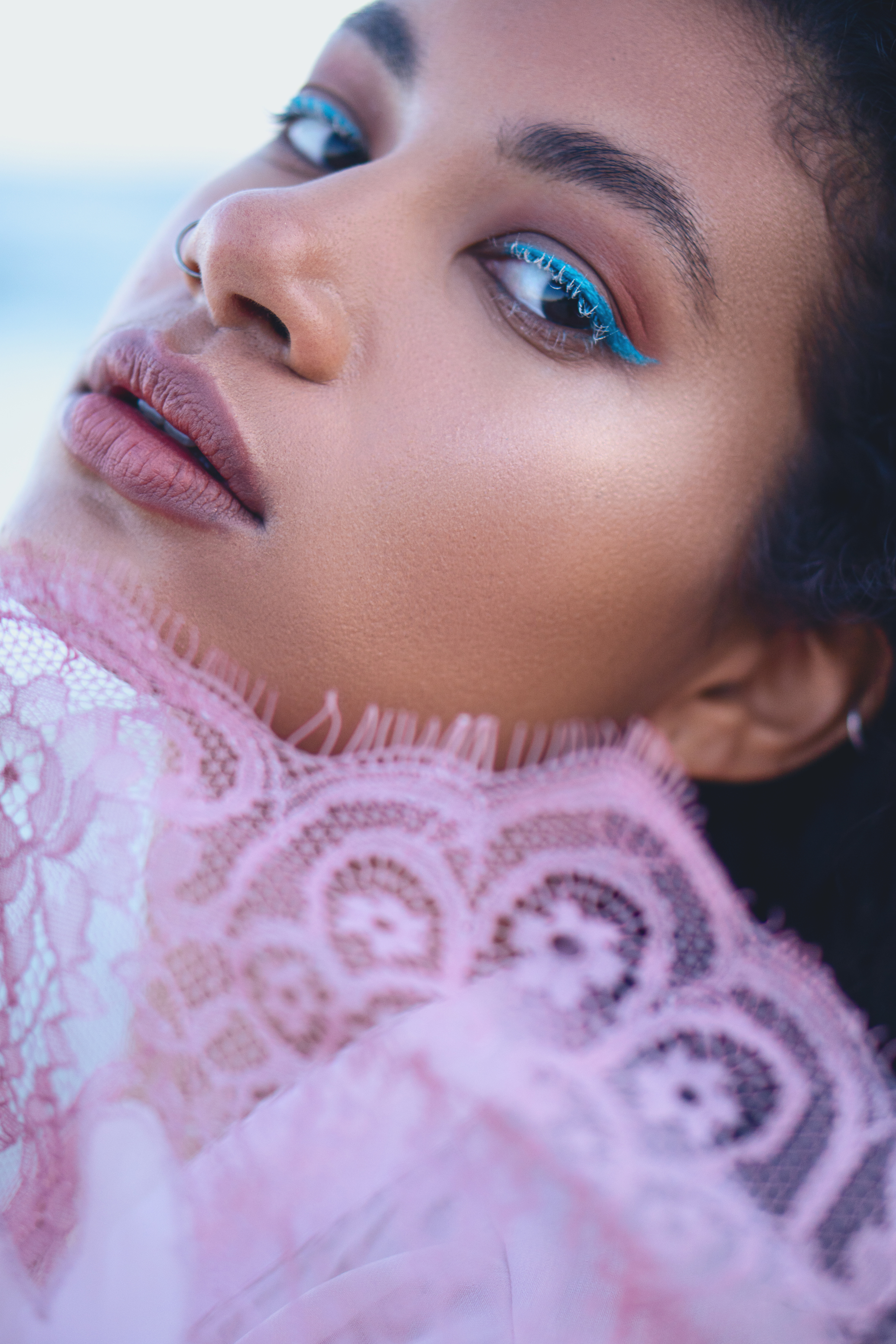Final close-up fashion portrait with refined skin, soft pink tones and vivid blue eye makeup