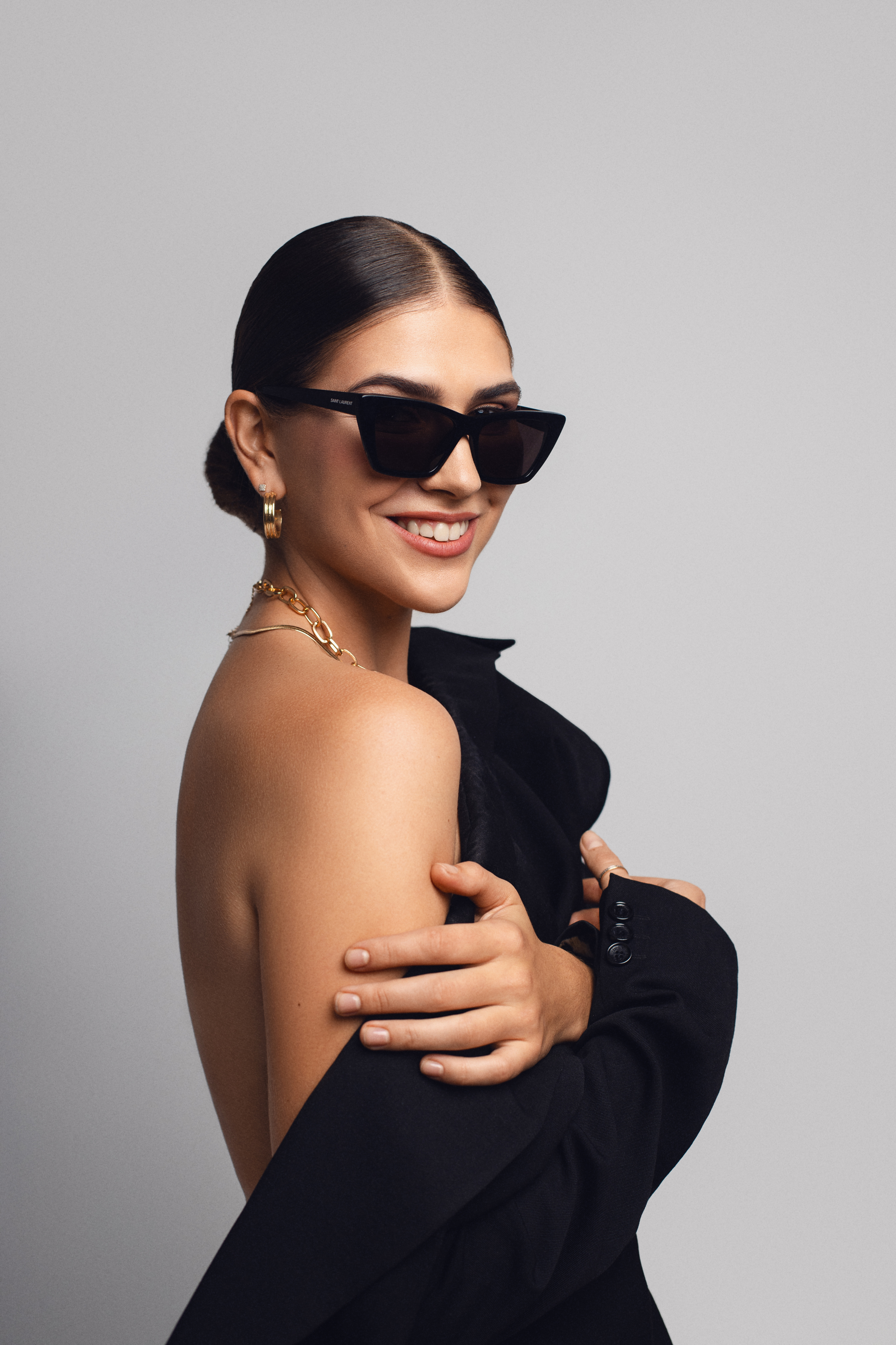 Fashion beauty portrait of a smiling woman in black sunglasses with natural skin texture and a clean neutral background