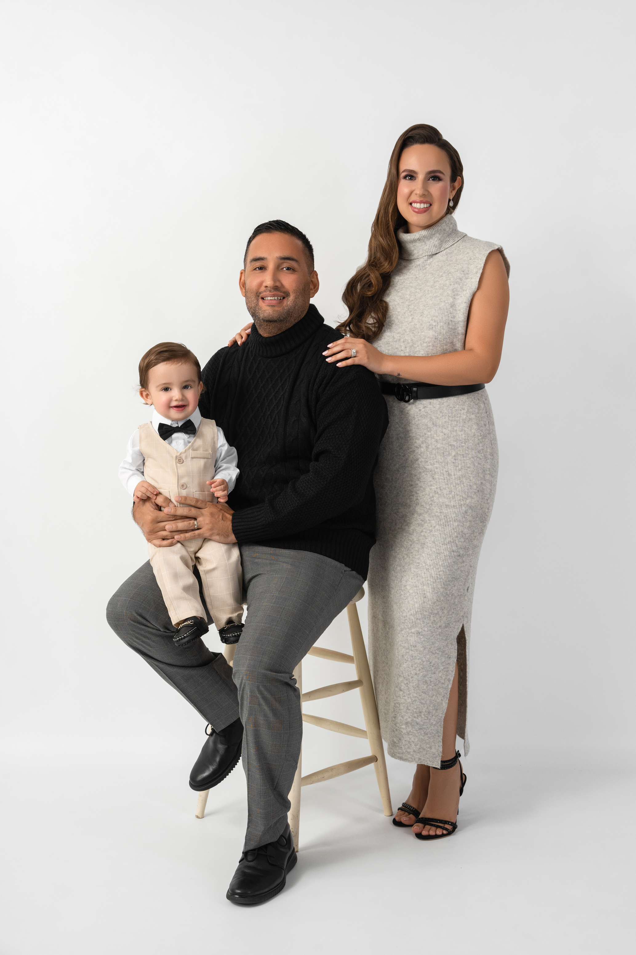 Studio portrait of two parents with their young child against a clean light background