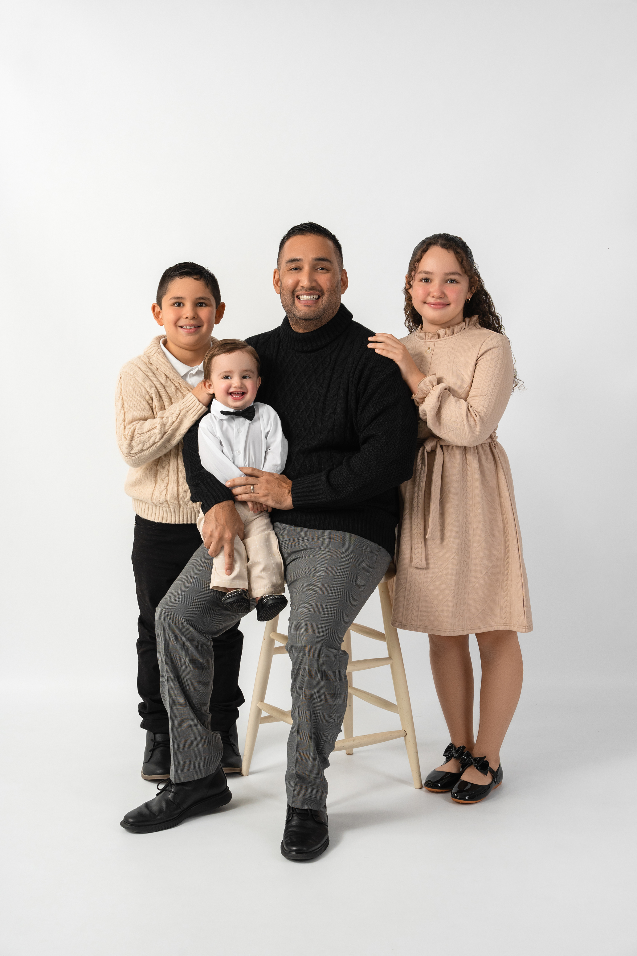 Studio family portrait of a father with three children in coordinated neutral clothing