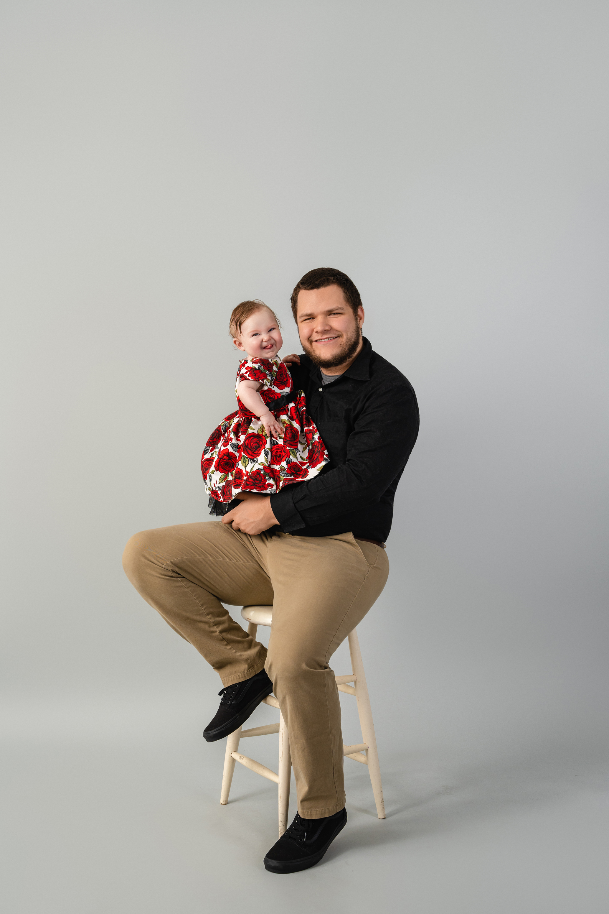 Studio portrait of a father seated with his baby against a clean gray background