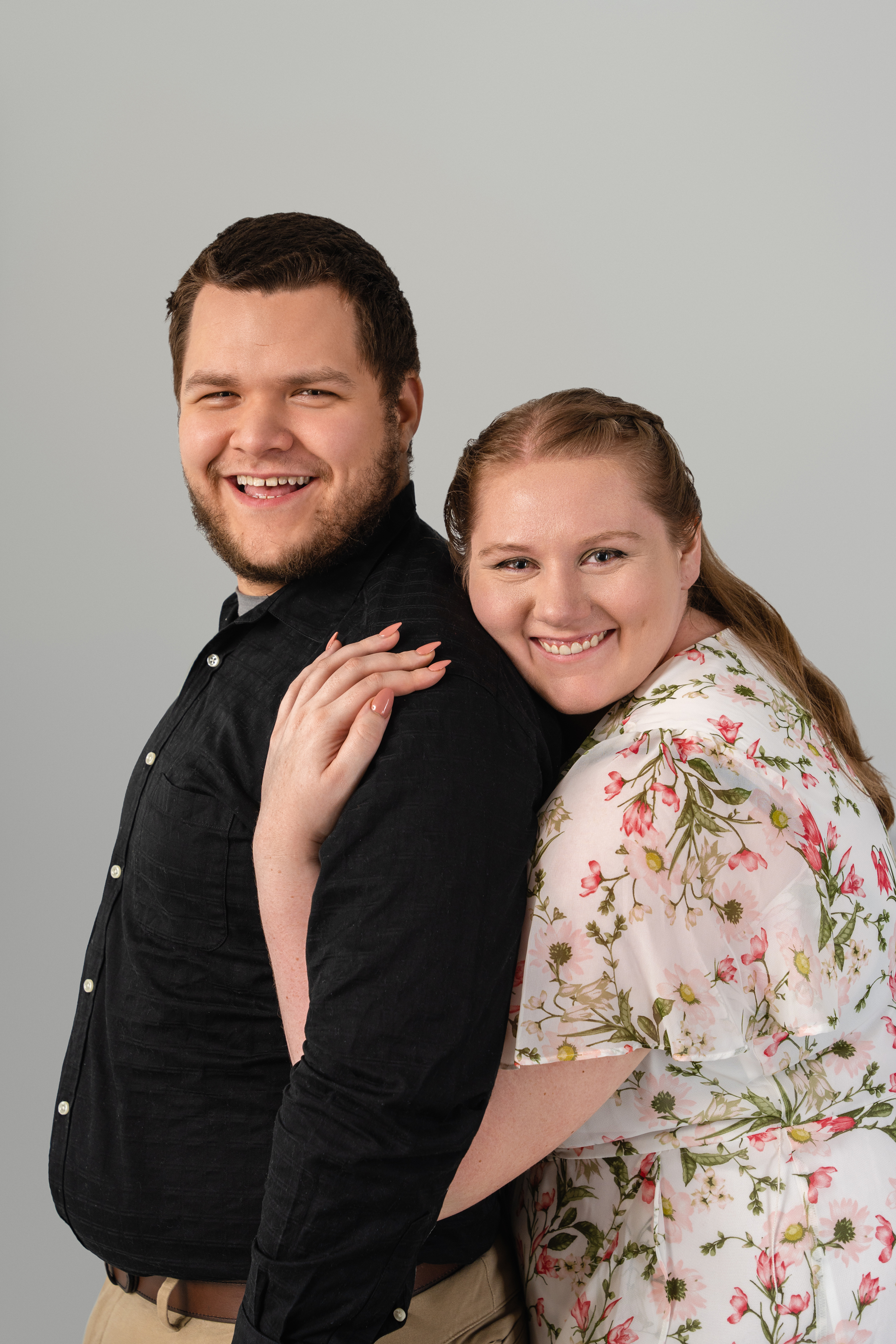 Studio portrait of a smiling couple posing together against a soft gray background