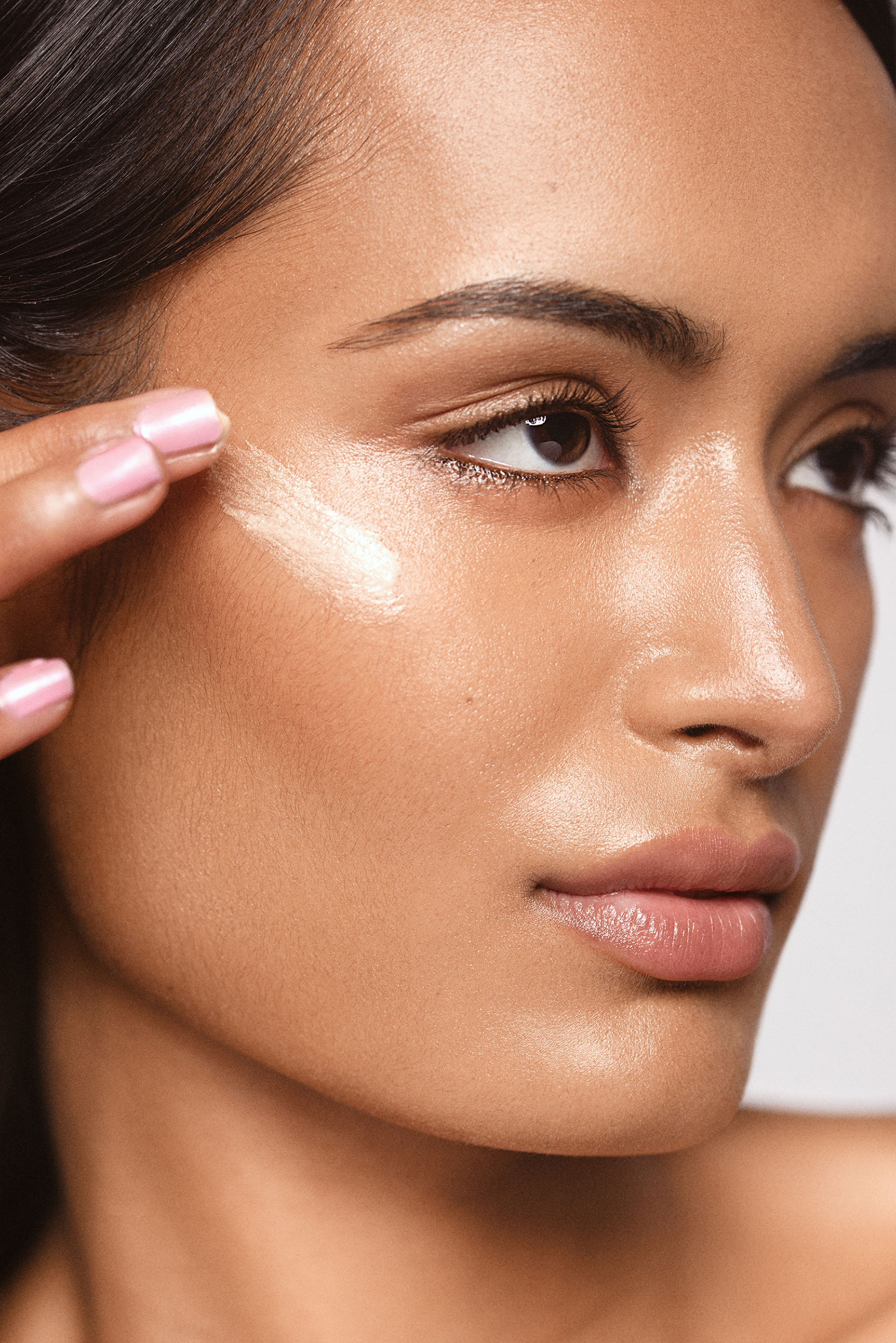 Beauty close-up with refined natural skin texture, luminous highlights and glossy neutral makeup