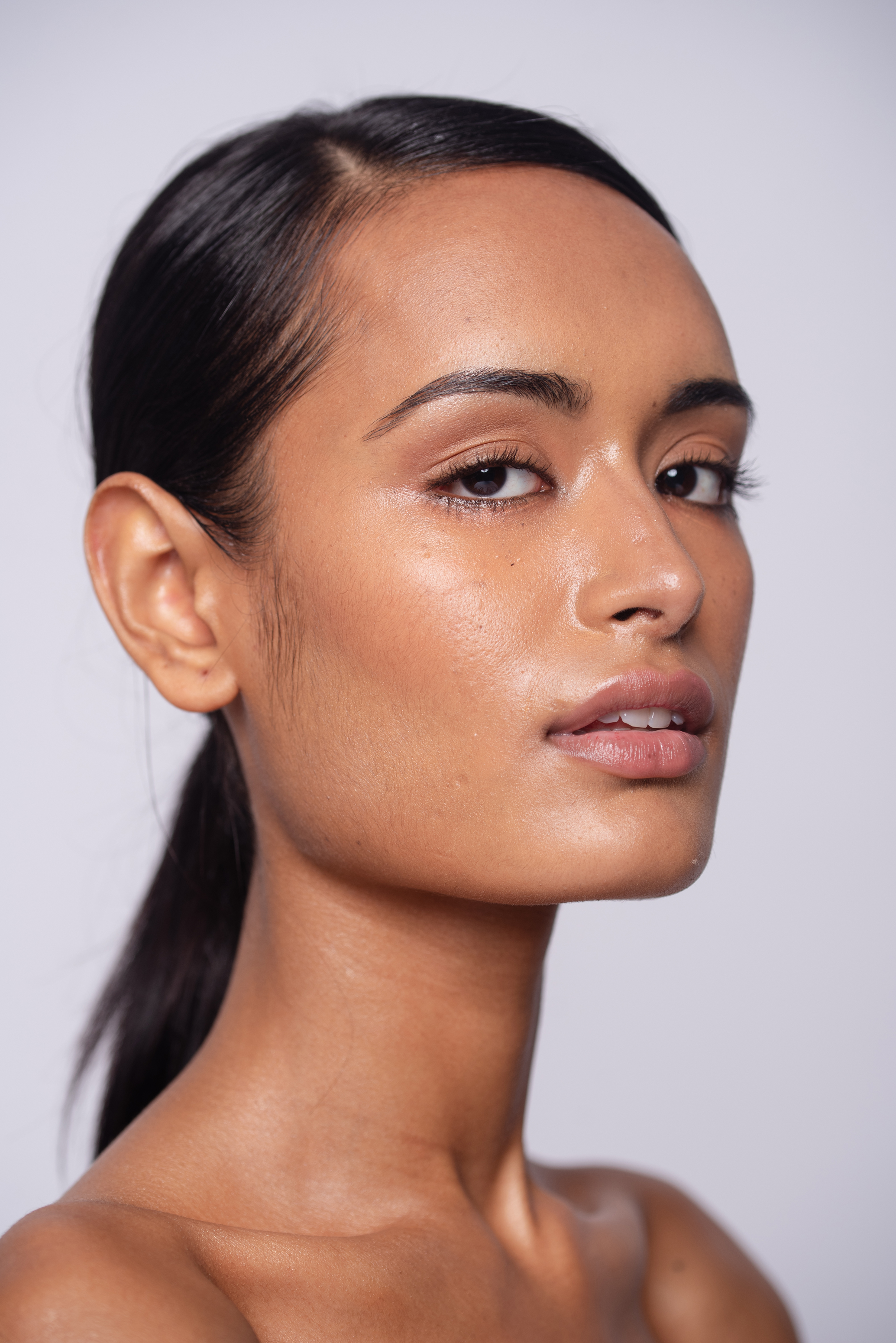 Beauty portrait before final retouching, showing a woman with sleek dark hair and natural luminous makeup
