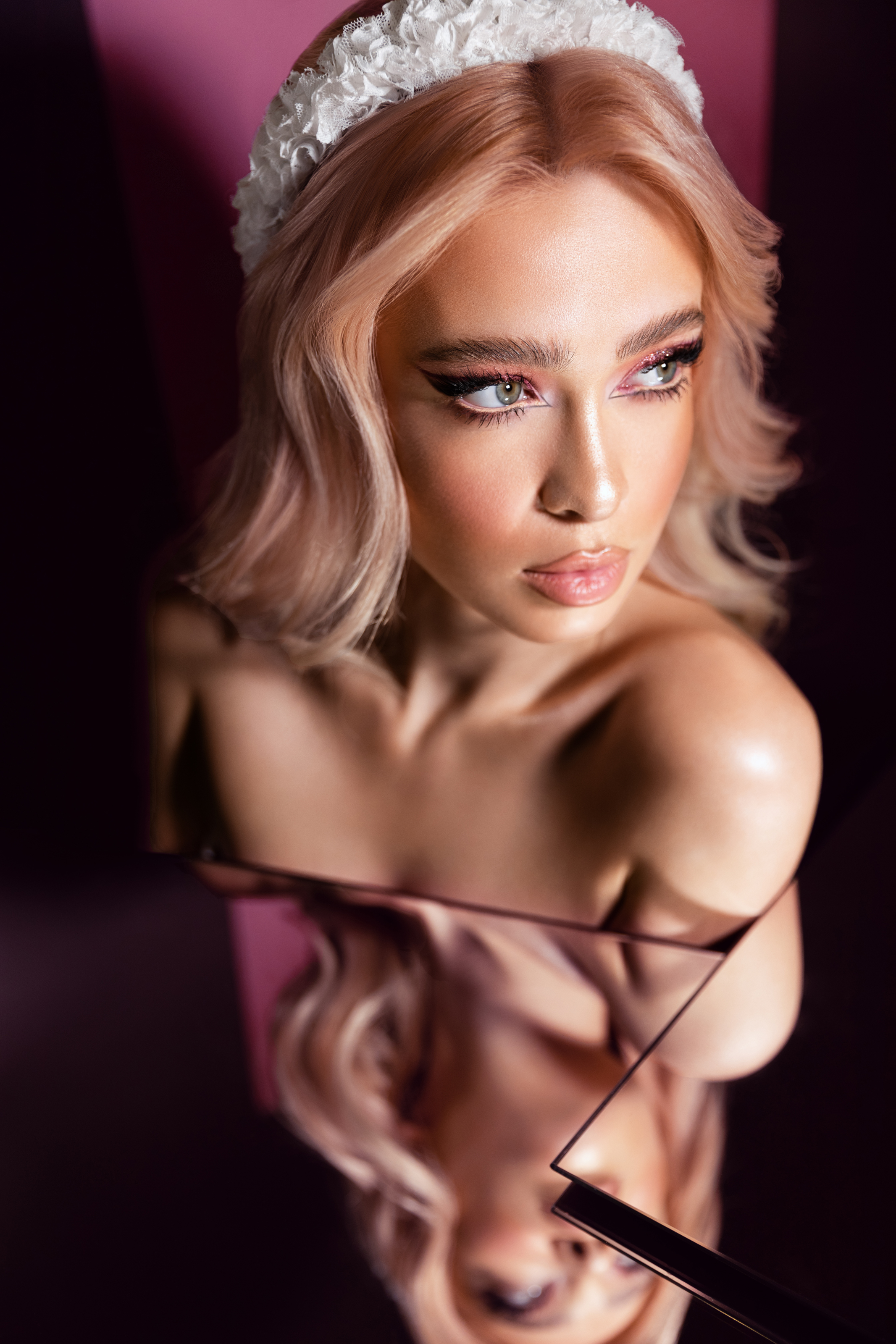 Beauty portrait, featuring a woman with dramatic eye makeup photographed through a mirror reflection