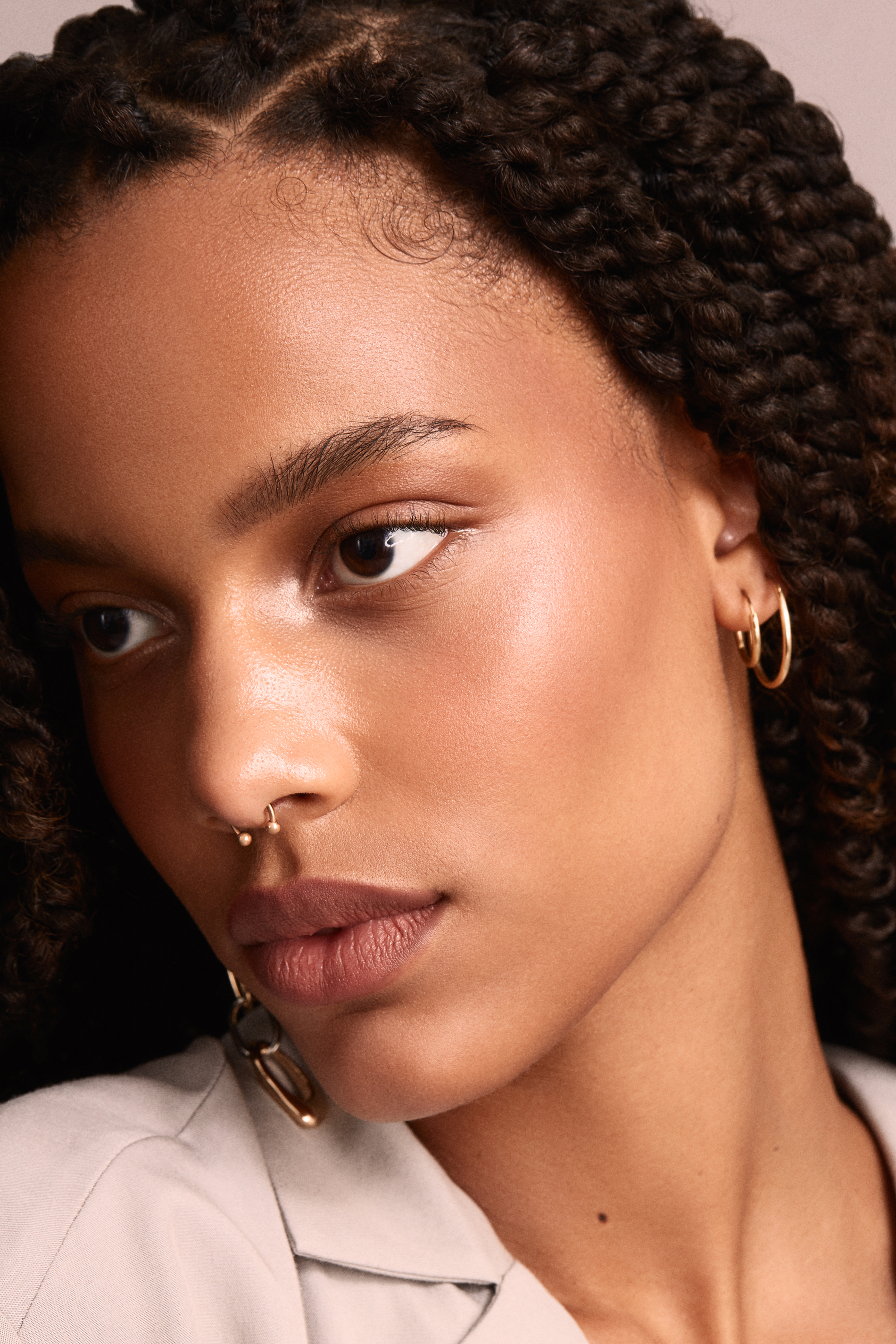 Close-up beauty portrait with braided hair, warm skin tones and soft dusty-pink color grading