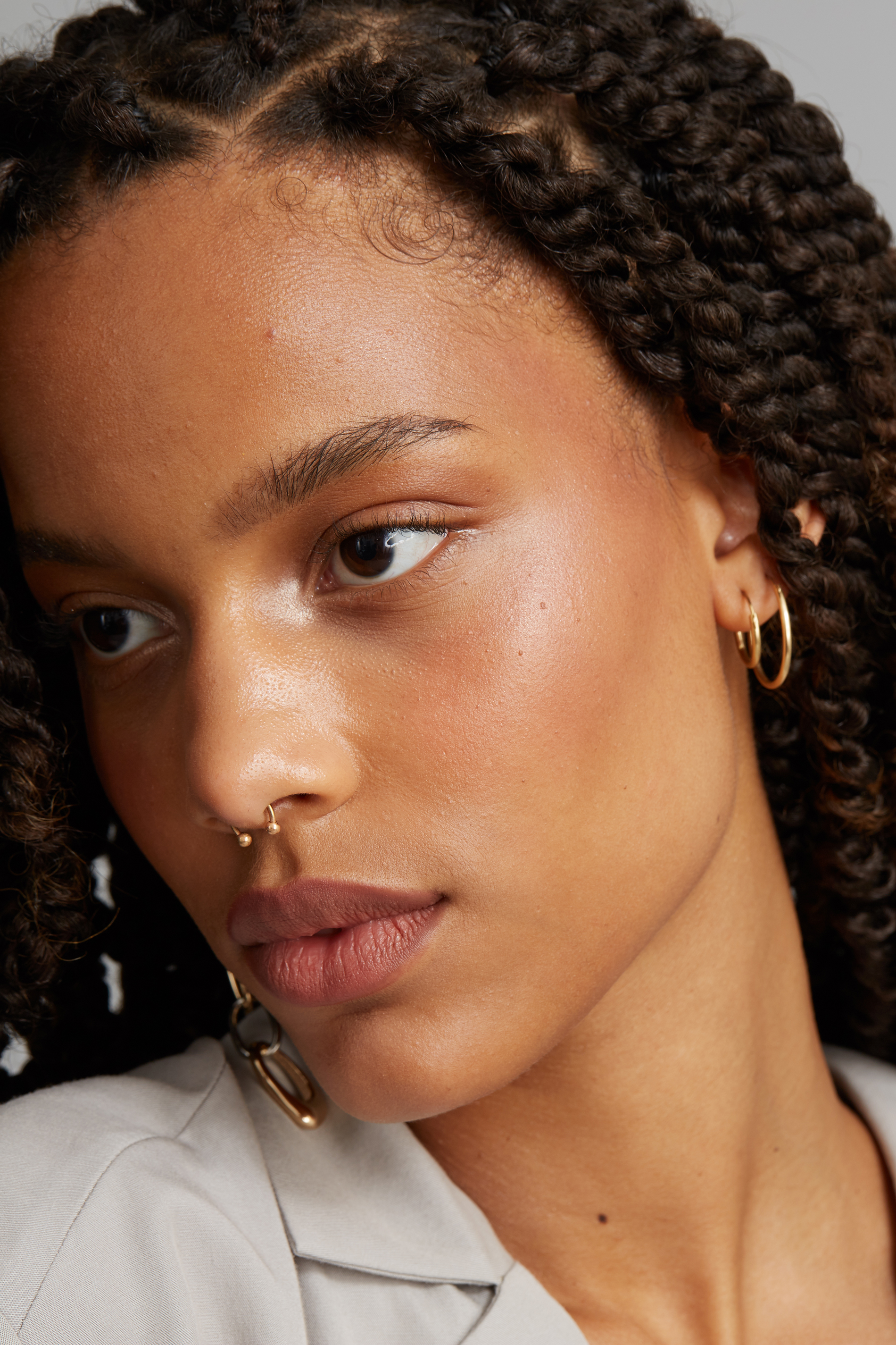 Beauty portrait before retouching, with braided hair and natural skin texture in a close three-quarter view