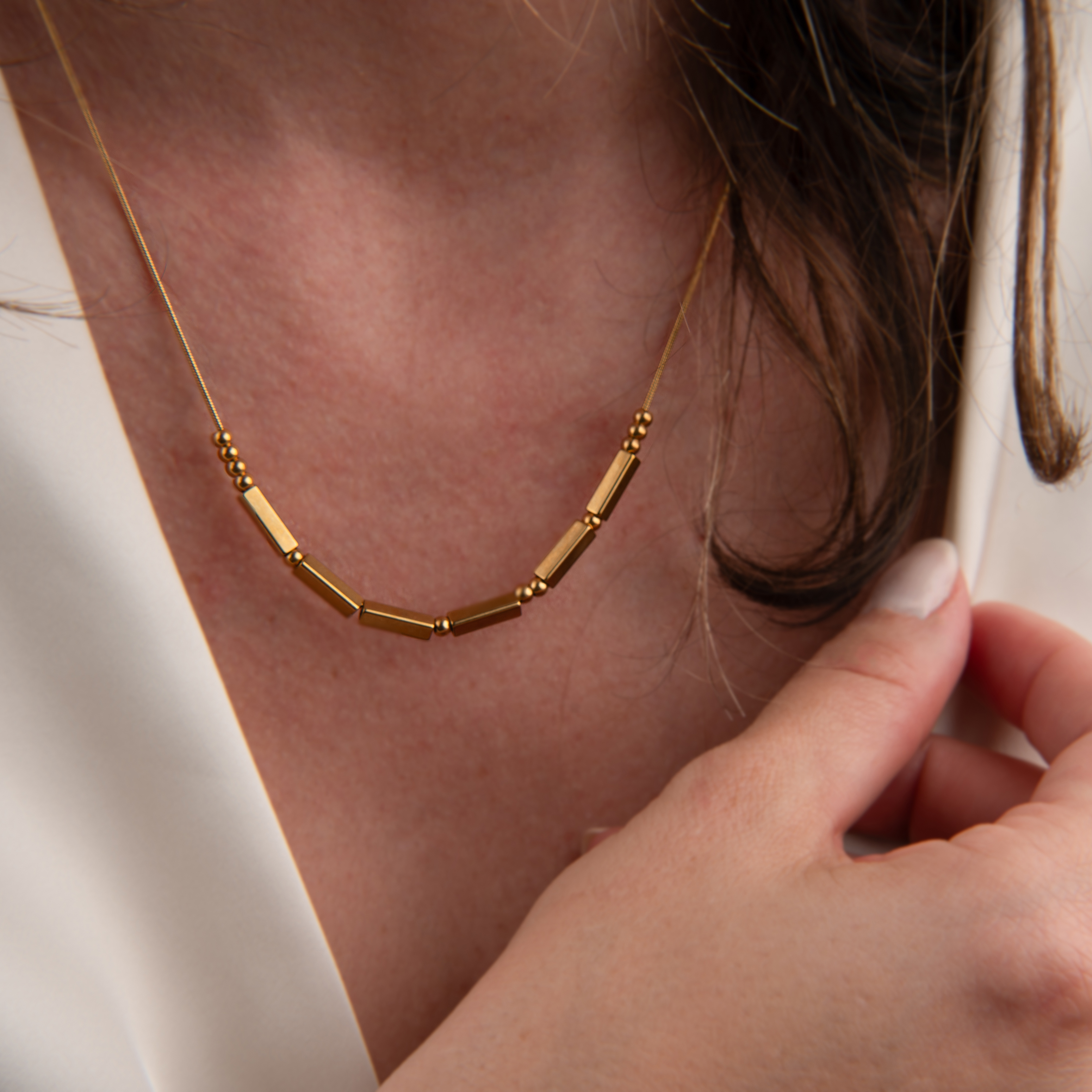 Jewelry image before retouching, showing a delicate gold necklace worn with a white blouse
