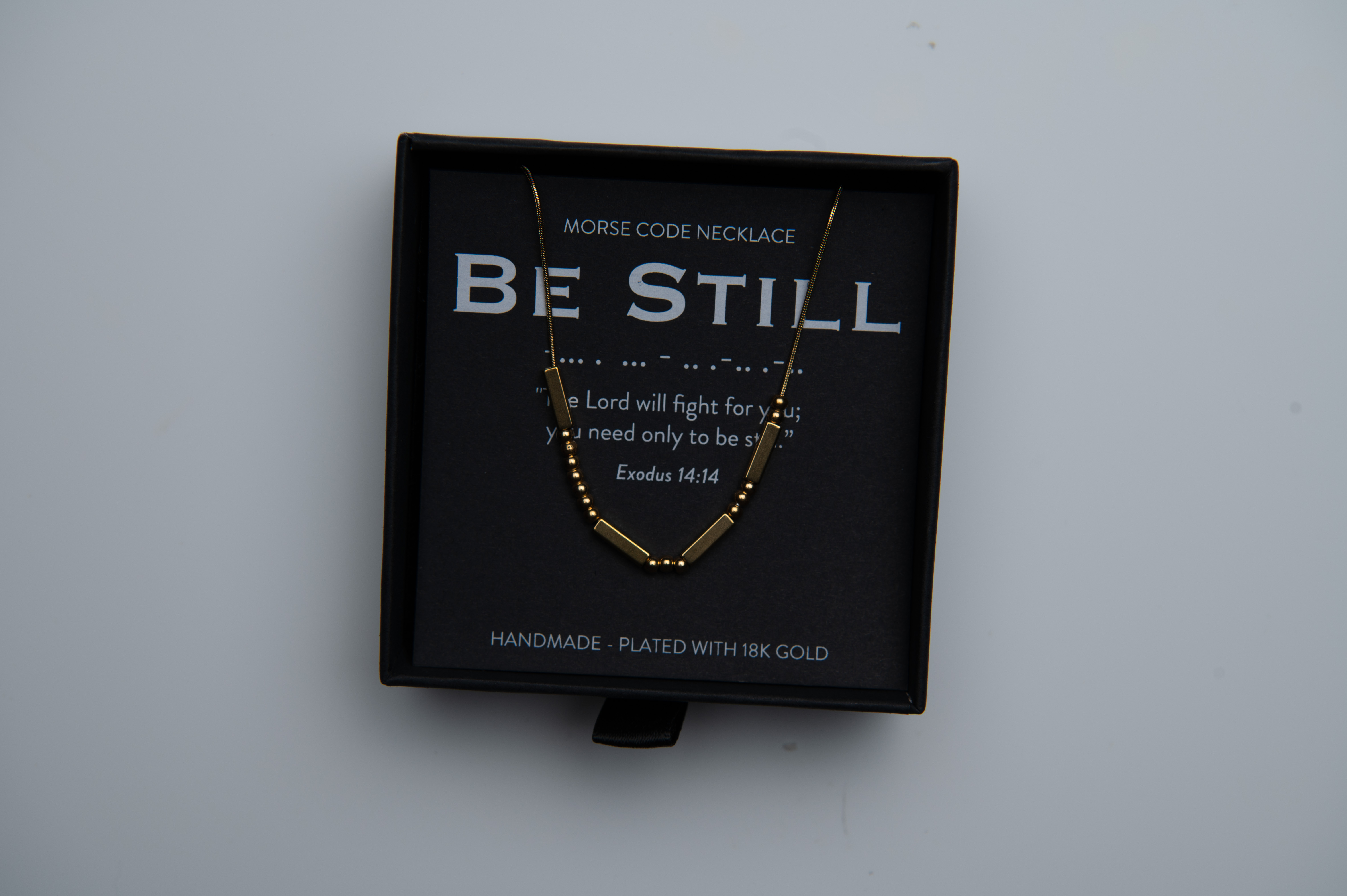 Morse code necklace product image before retouching, photographed with black branded packaging
