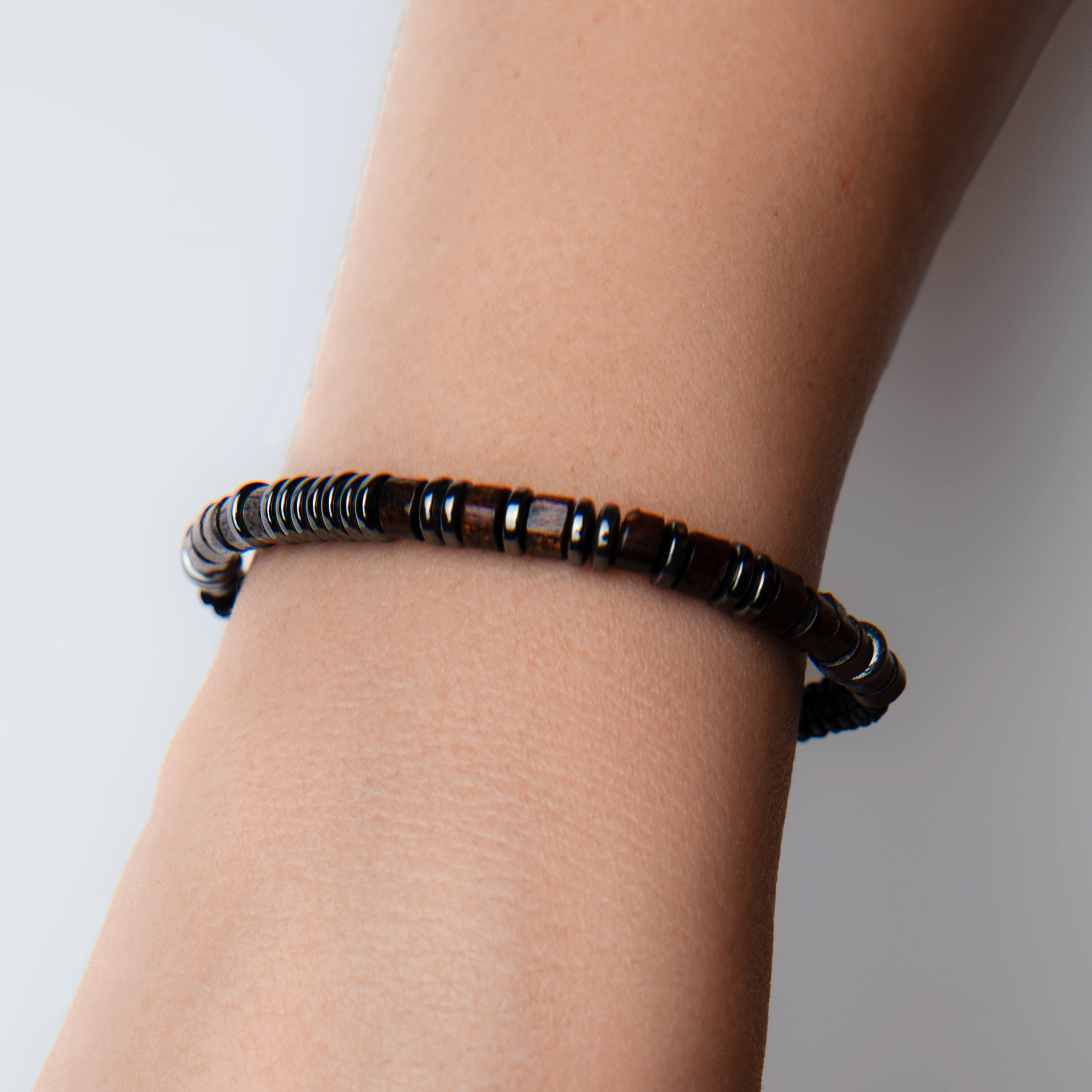 Close-up product image of a dark beaded bracelet worn on the wrist with clean skin tones and crisp bead detail