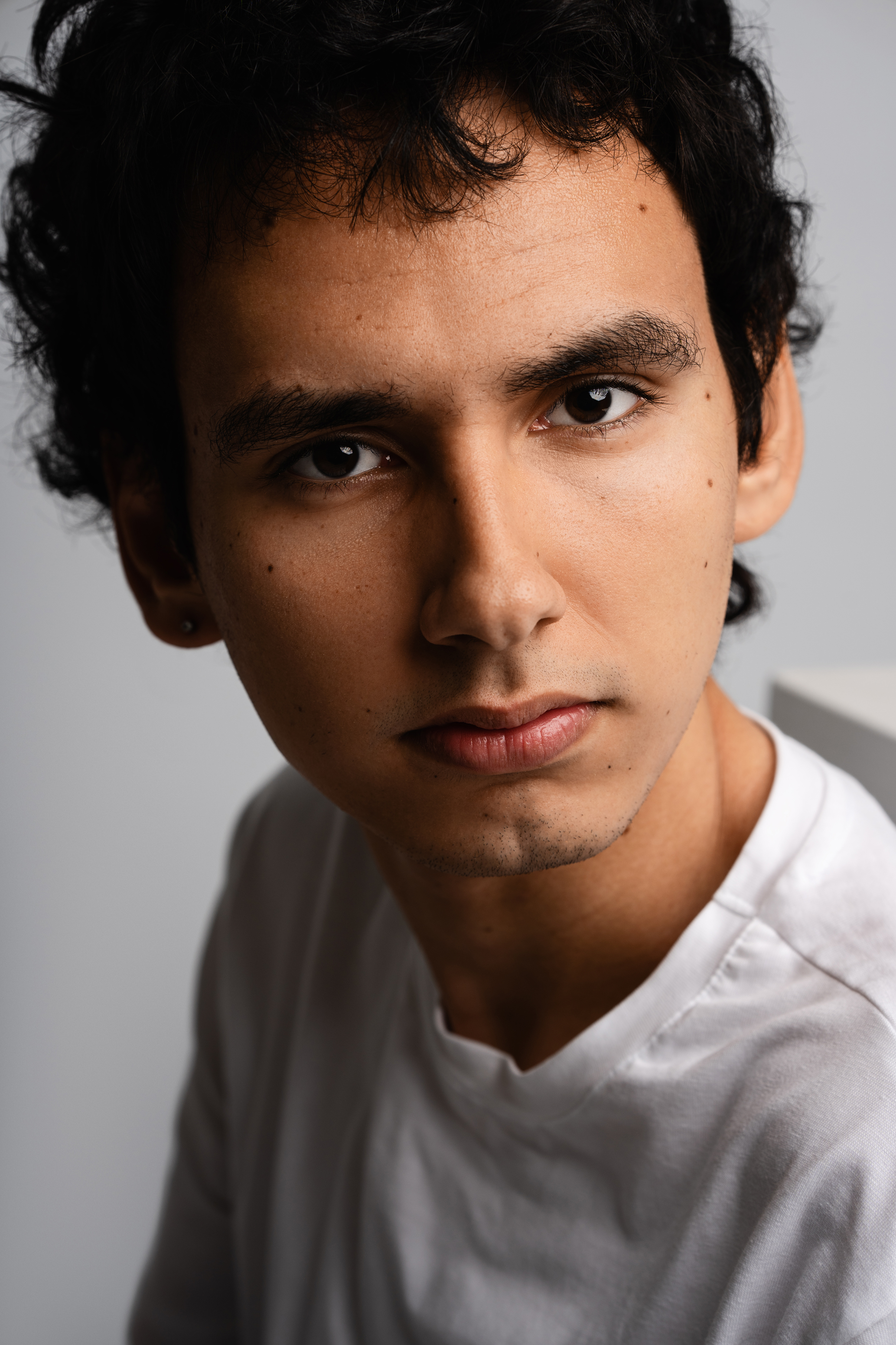 Close-up studio portrait of a man in a white T-shirt with soft directional light and a neutral background