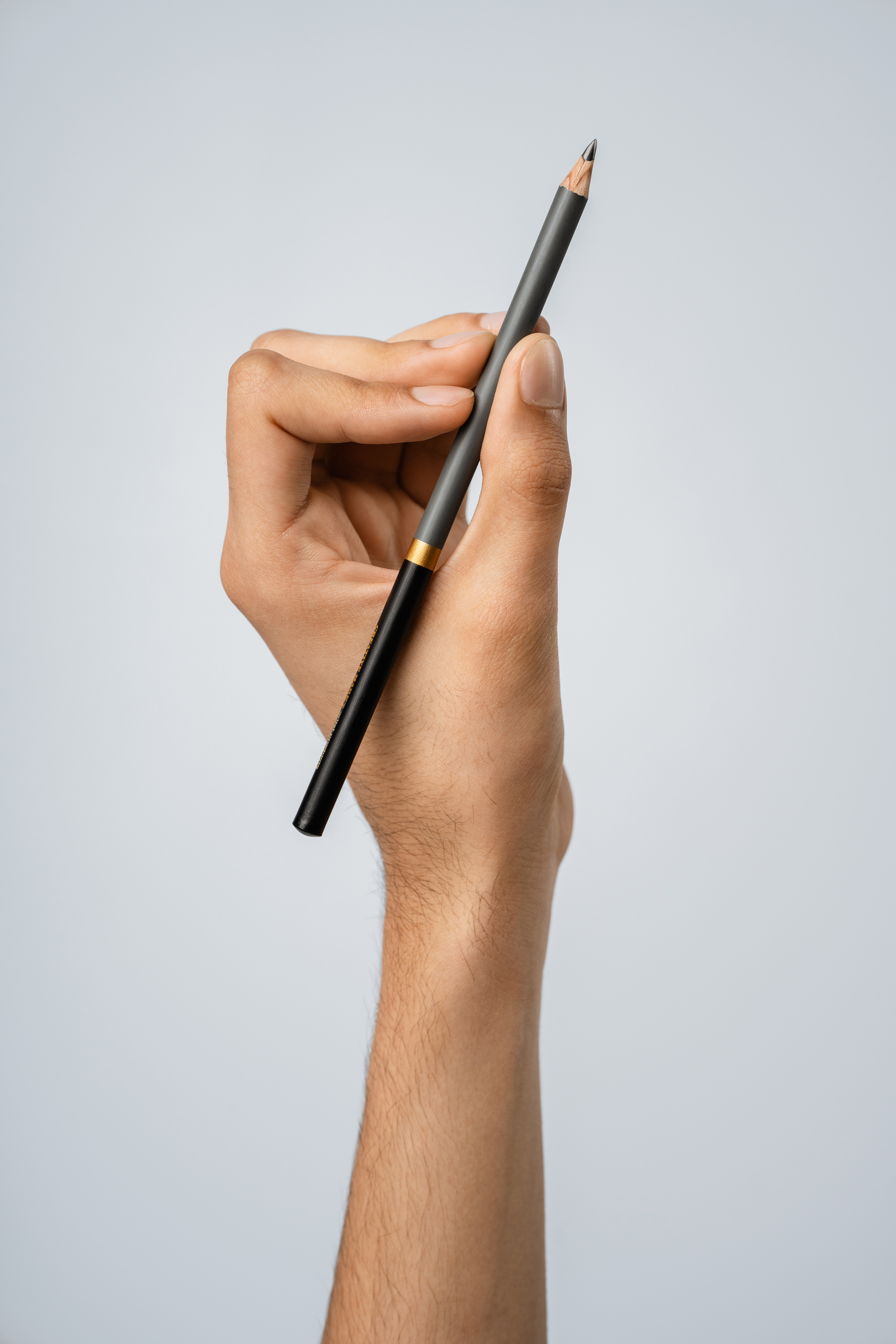 Detail portrait of a hand holding a drawing pencil against a clean light background
