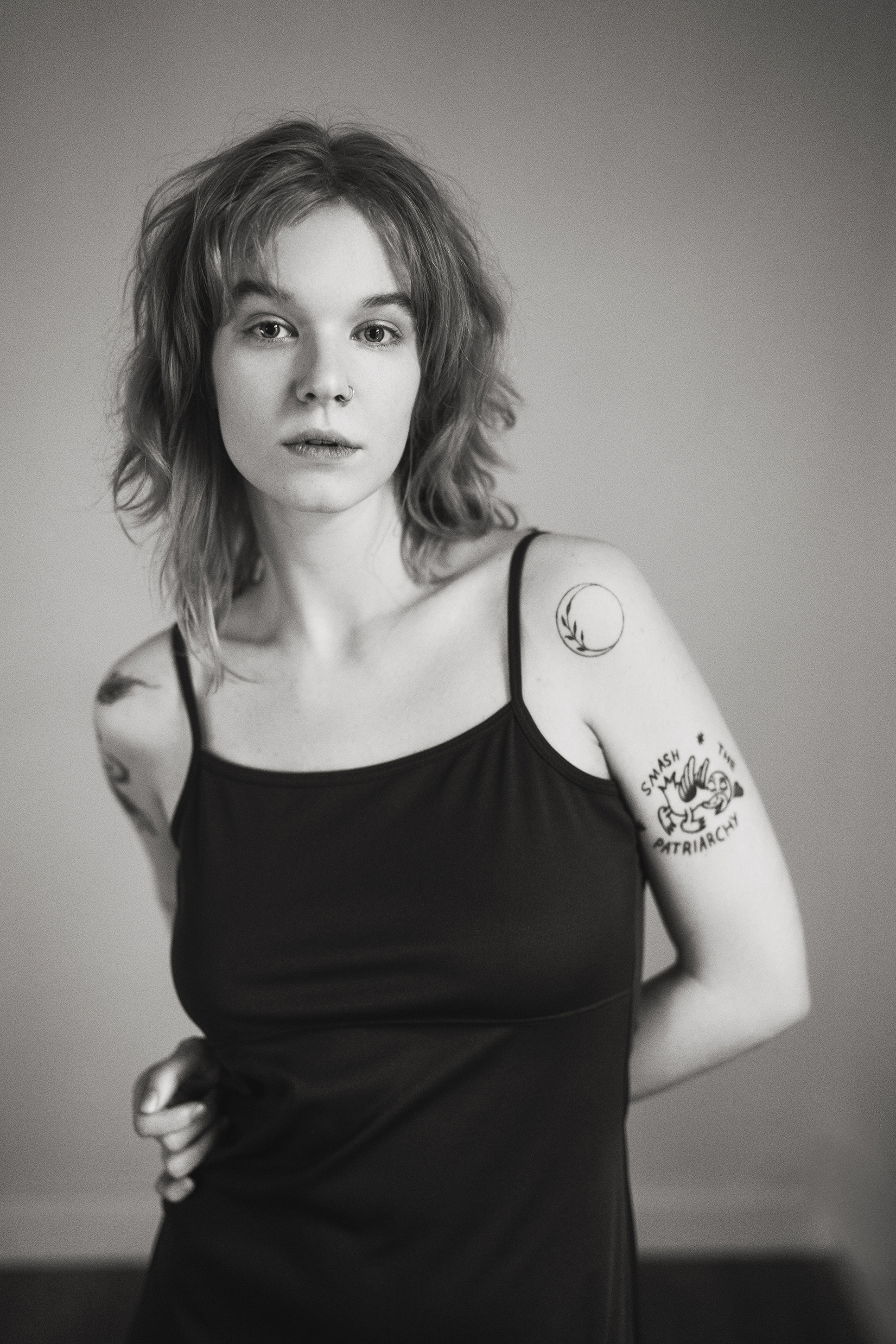 Black-and-white close-up portrait of a woman in a dark slip dress against a soft neutral background