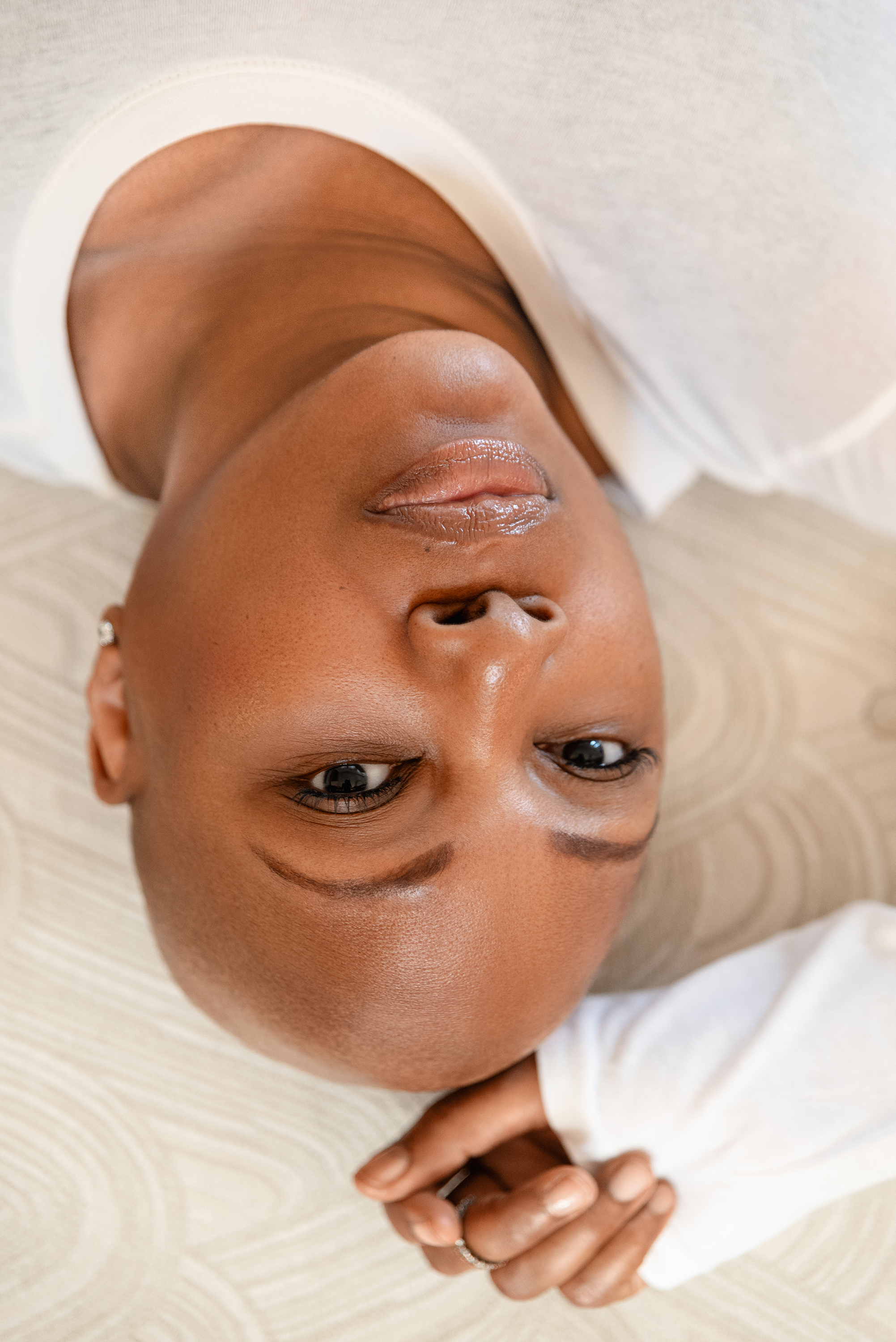 Creative close-up portrait of a woman with a shaved head reclining and looking toward the camera