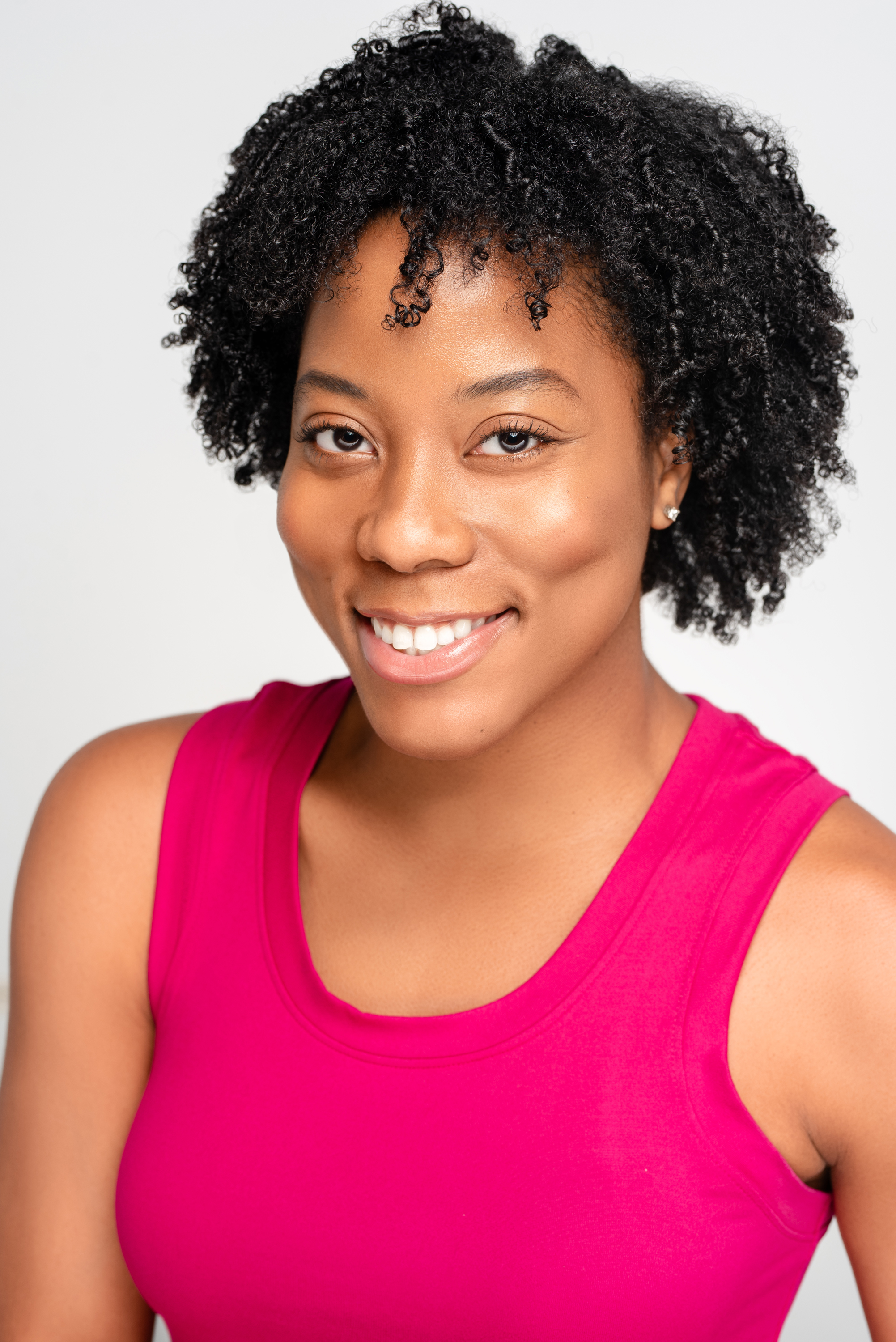 Bright personal branding headshot of a smiling woman in a pink top against a clean light background