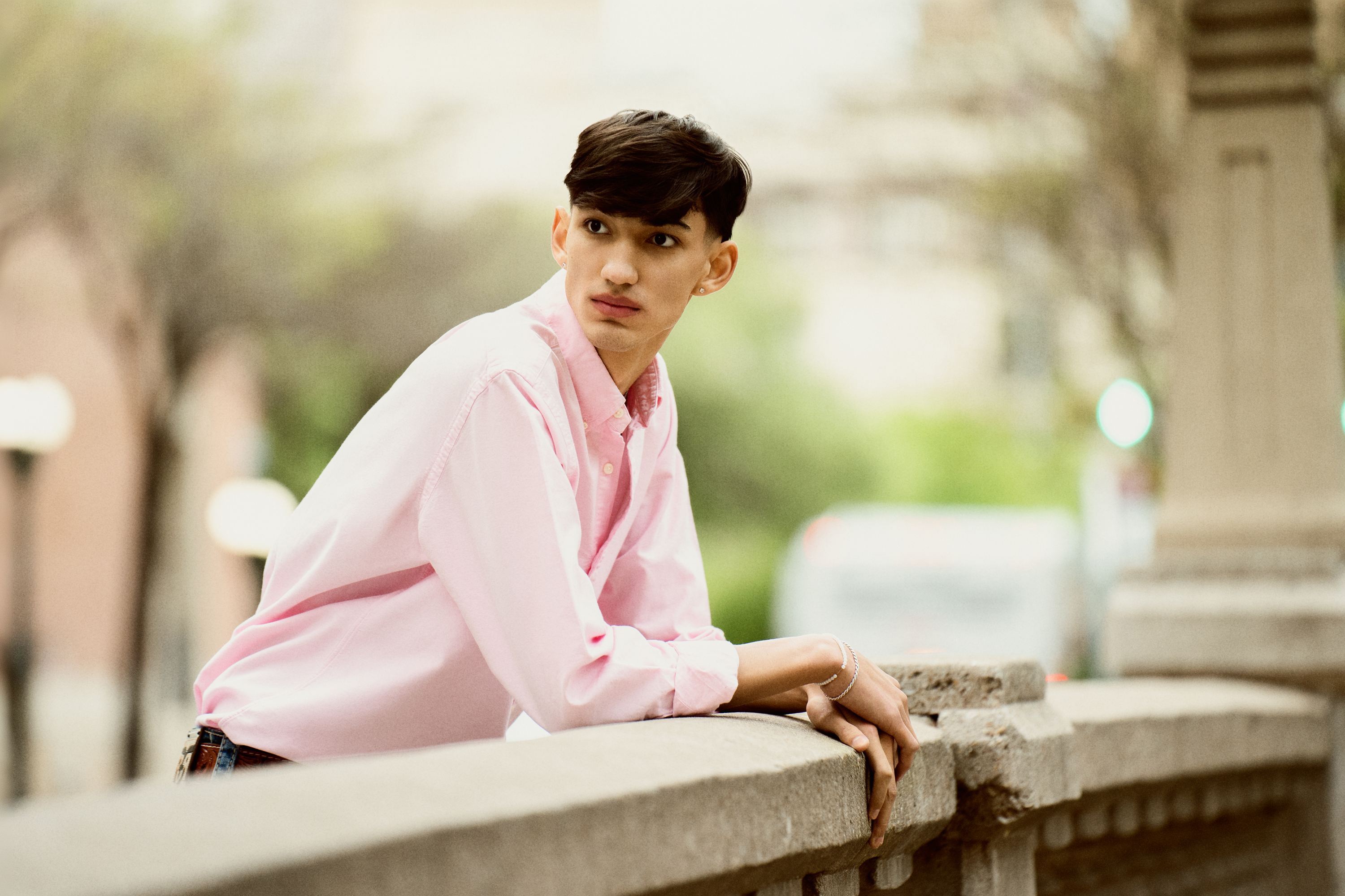 horizontal senior portrait of a teenage boy leaning on a stone railing outdoors