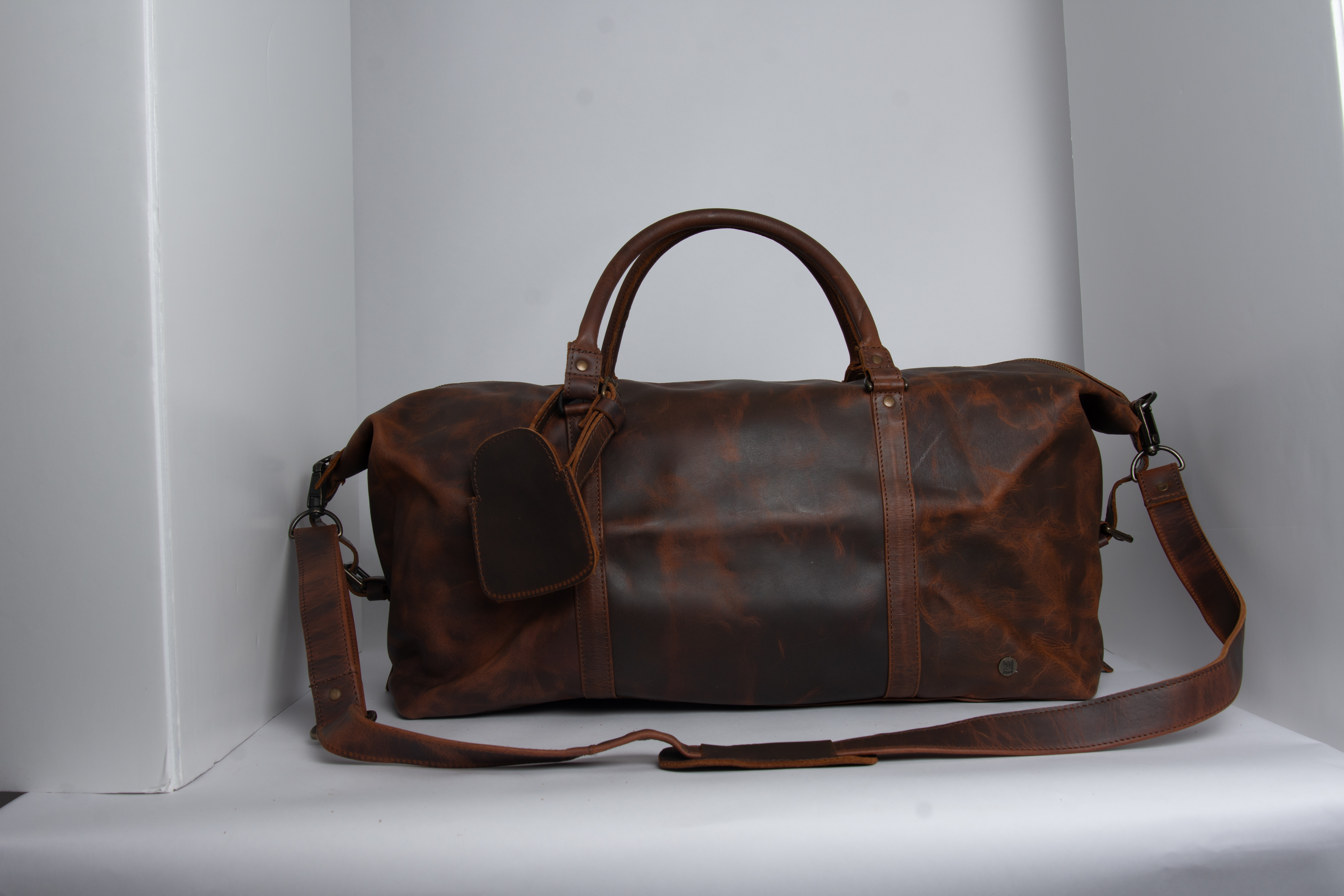 Waxy brown leather duffle bag photographed in a studio setup before retouching