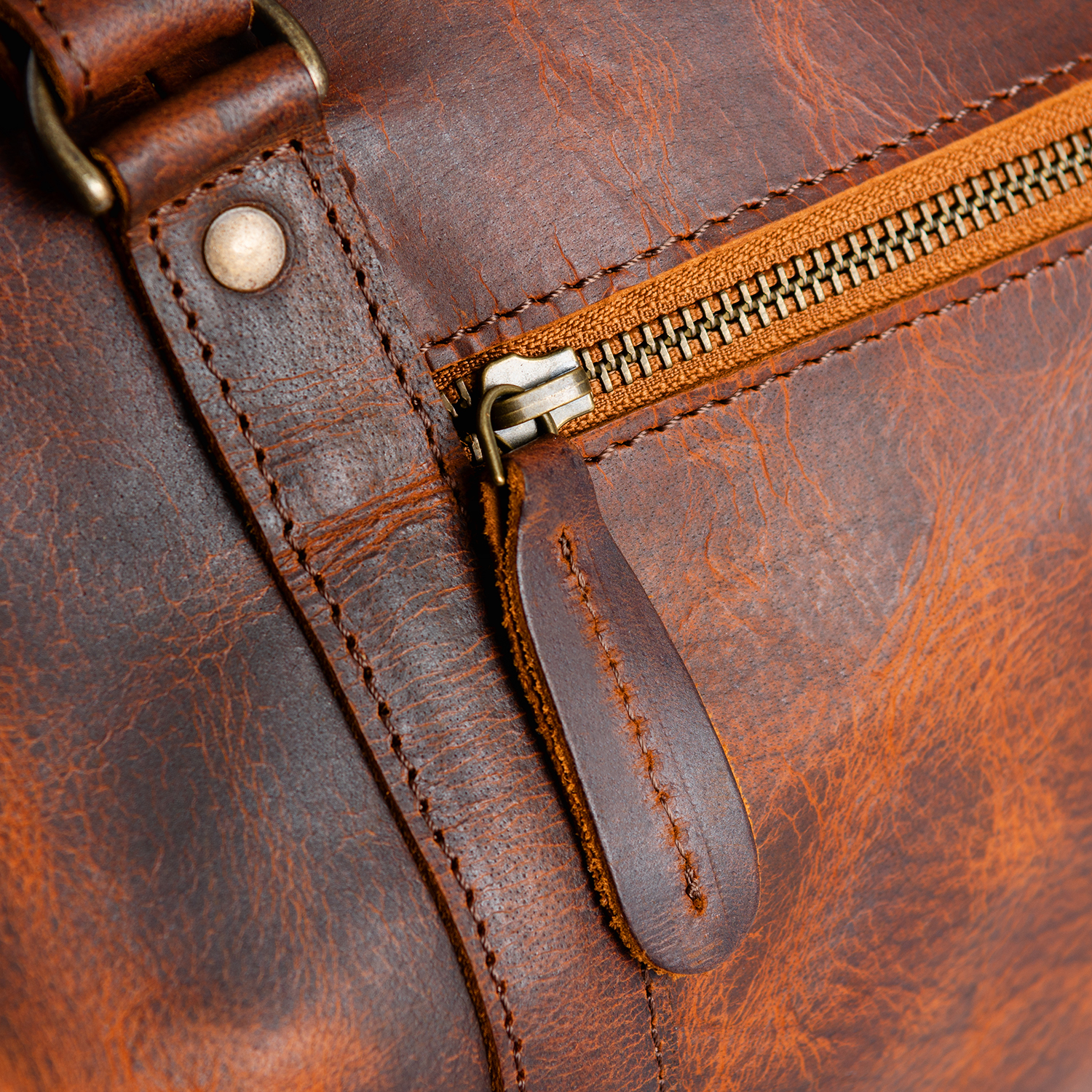 Close-up of a leather bag zipper, stitching and polished metal hardware