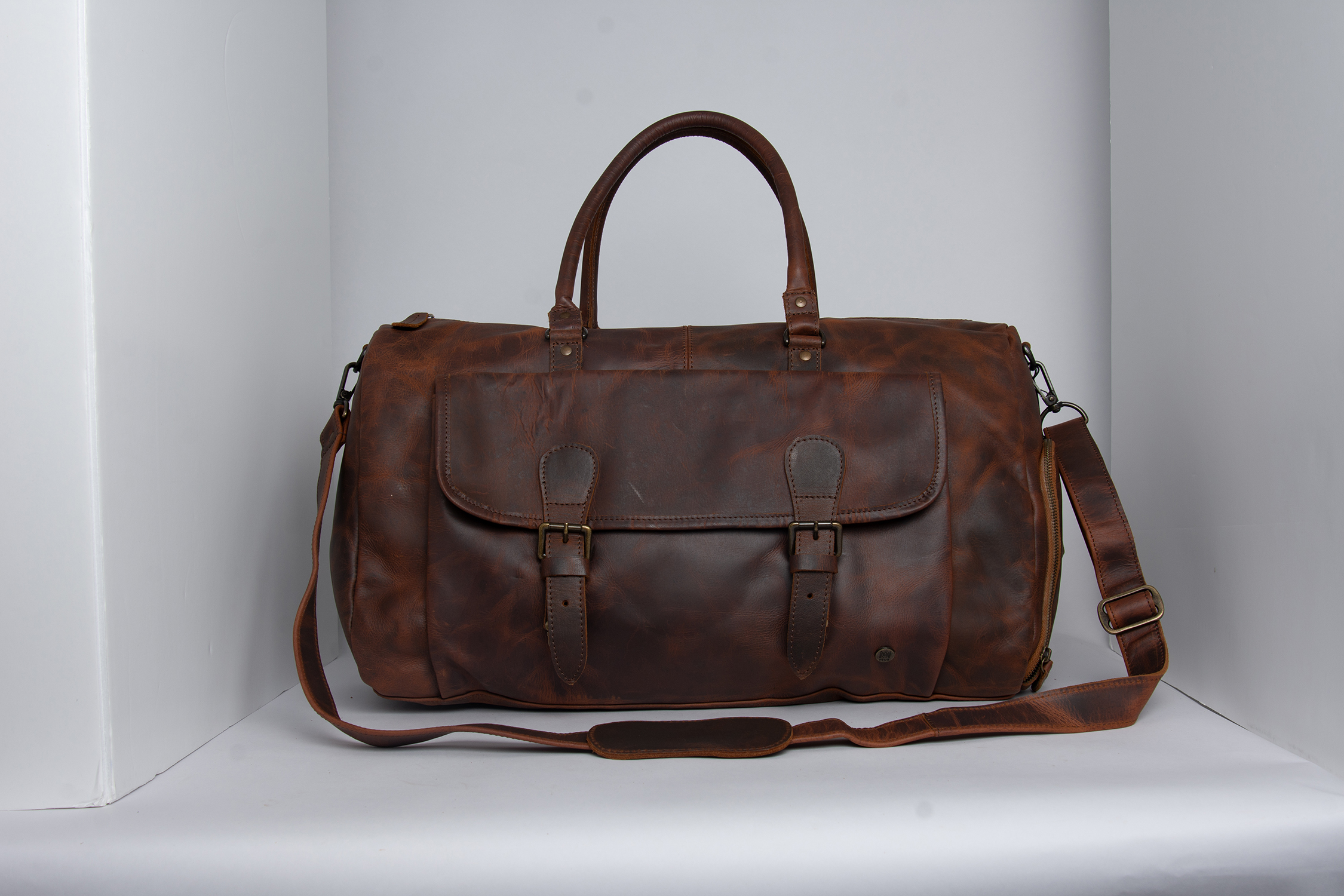 Structured brown leather overnight bag photographed in a studio setup before retouching