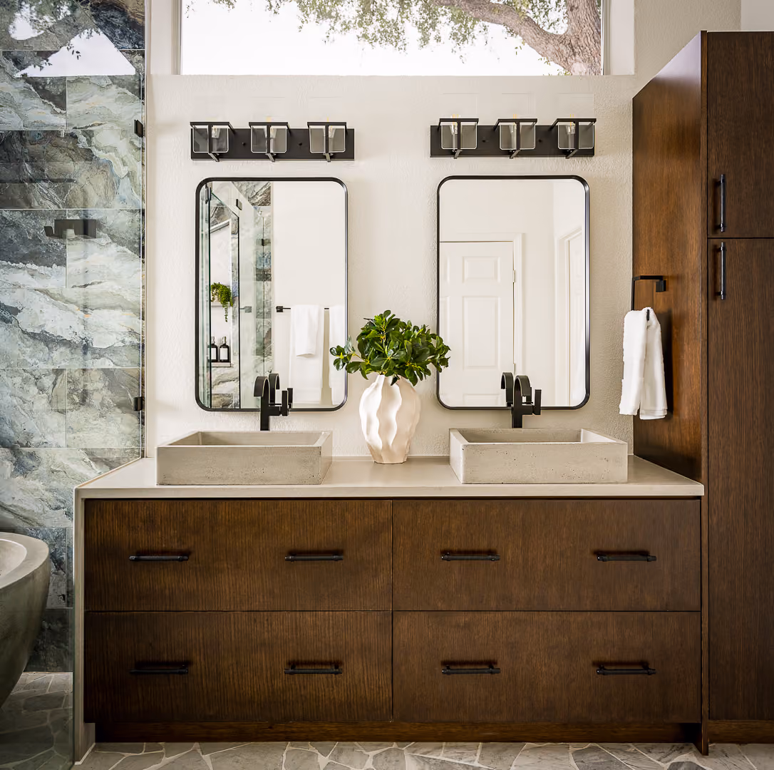 Modern bathroom with dual rectangular sinks, two mirrors, dark wood cabinetry, and green plant centerpiece.