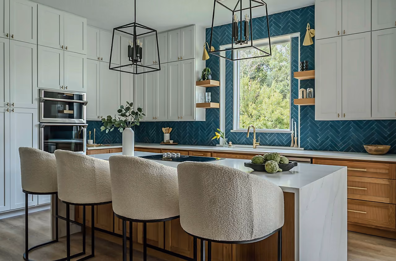 Modern kitchen with white and wood cabinets, blue tile backsplash, large island, and four upholstered stools.