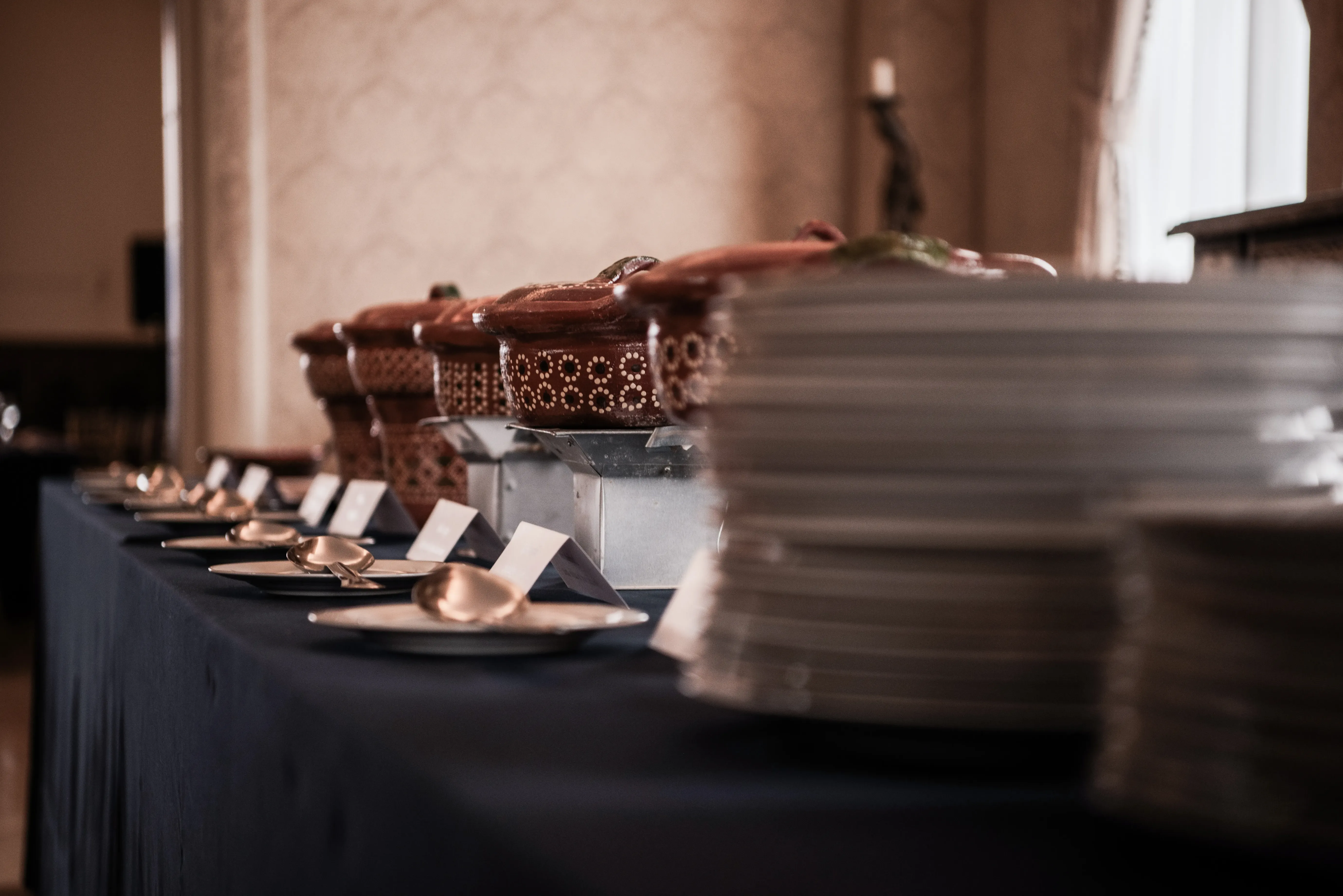 Creative angle for a food buffet, with cultural food containers and a dark blue tablecloth. 