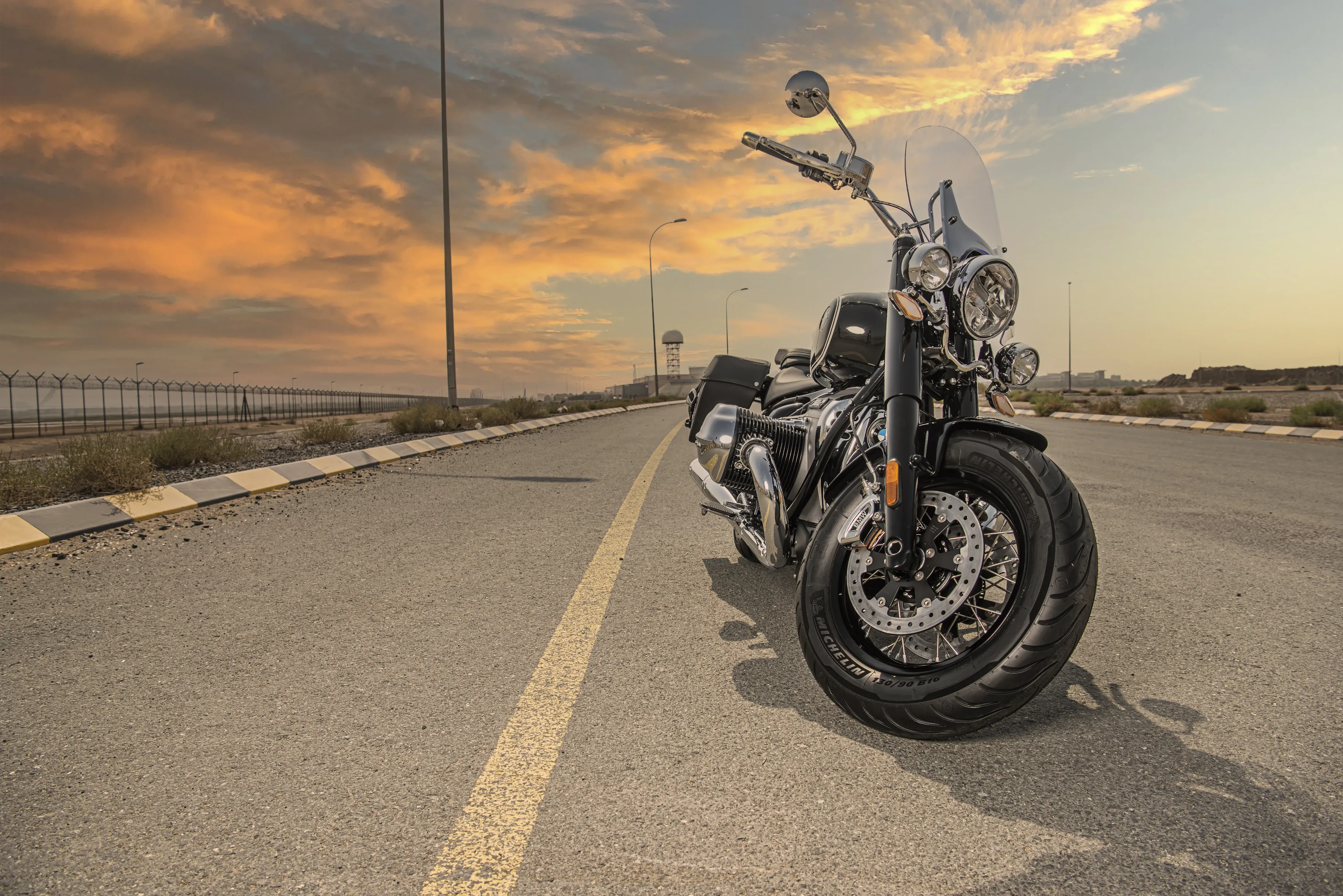 Low-angle shot of a BMW bike, taken during sunset with a cloudy sky in the background while the bike is on the pavement. The yellow line follows the fall angle.  