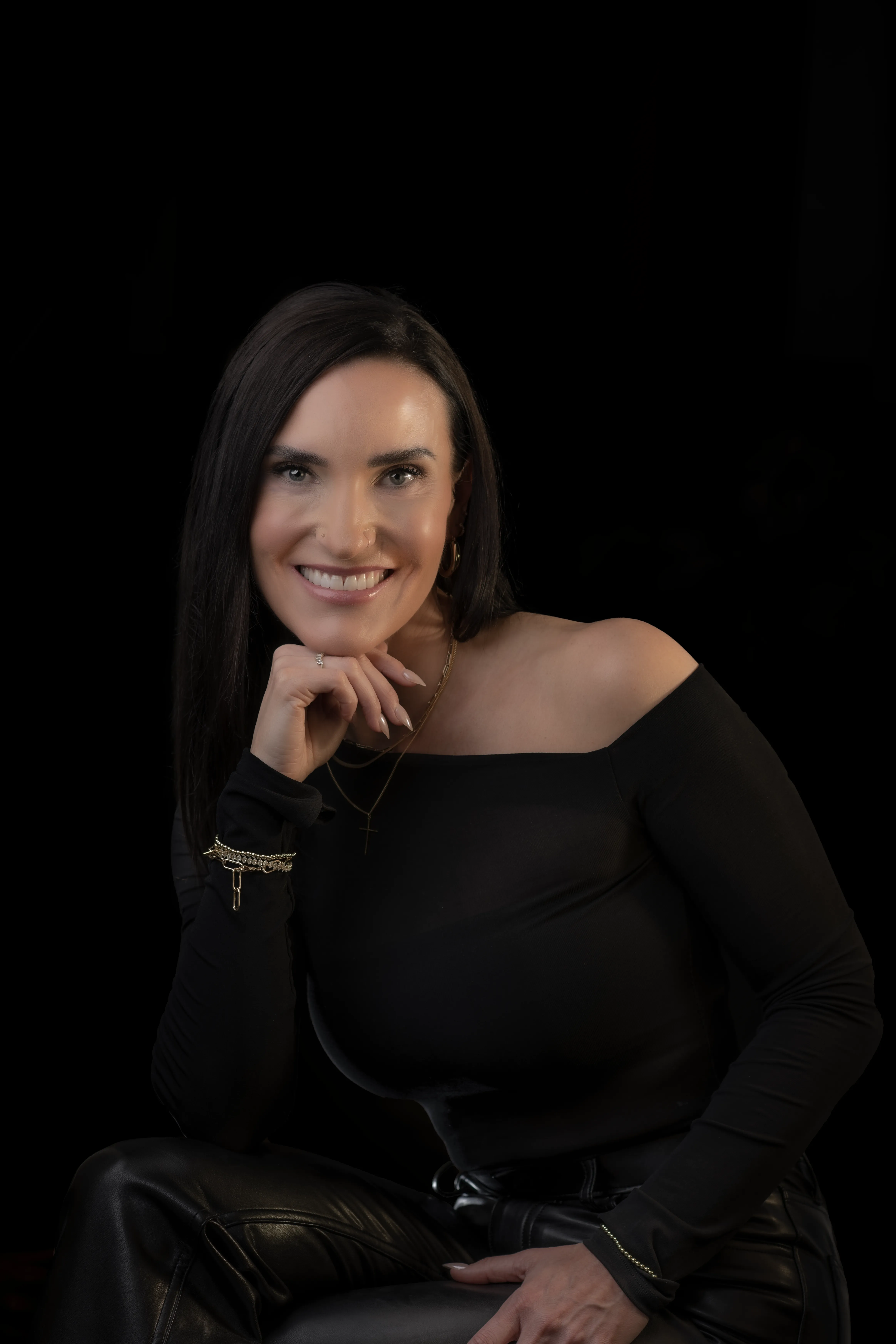 Personal portrait of a beautiful woman with black hair smiling, posing in a formal black dress.