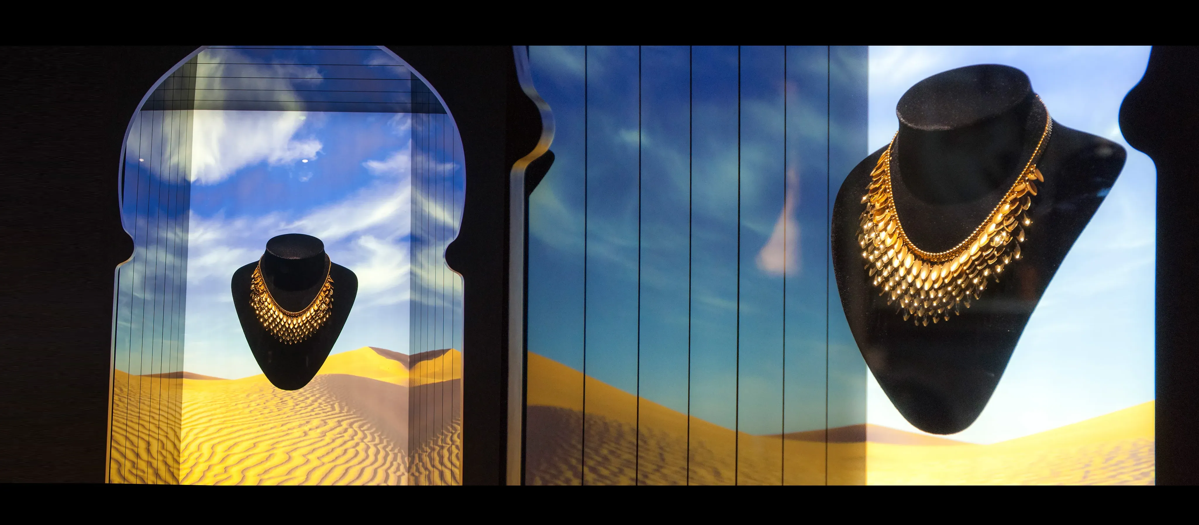 Levitating display unit, featuring gold necklaces with a custom desert graphic in the background that is backlit.