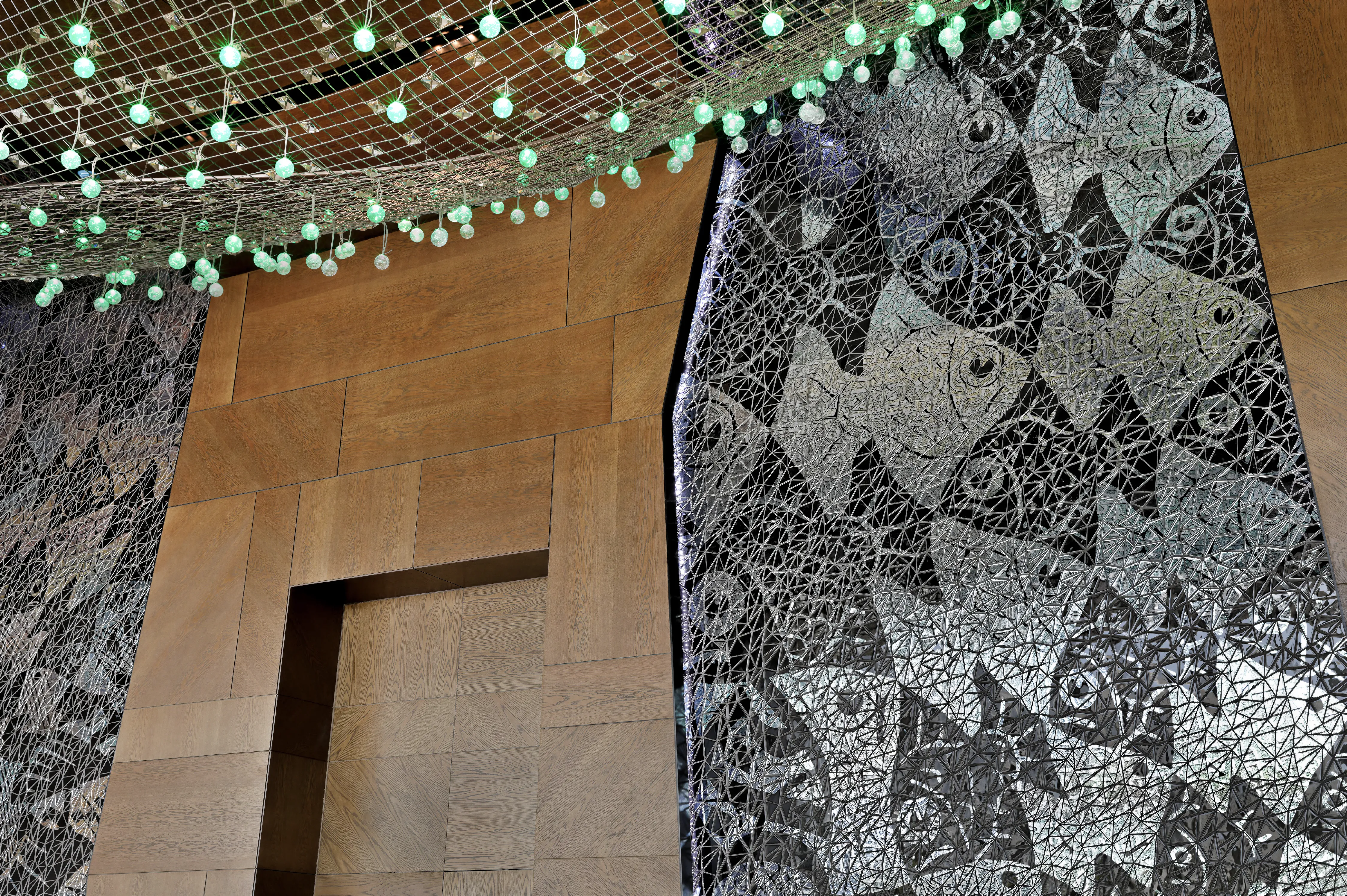 close up of a resort ballroom main hall, featuring large-scale appropriation art and a custom ceiling. Wood cladding and recessed lighting. Dark stone floor. 40ft+ high, with the artwork continuing through the ceiling, above the lighting feature. 
