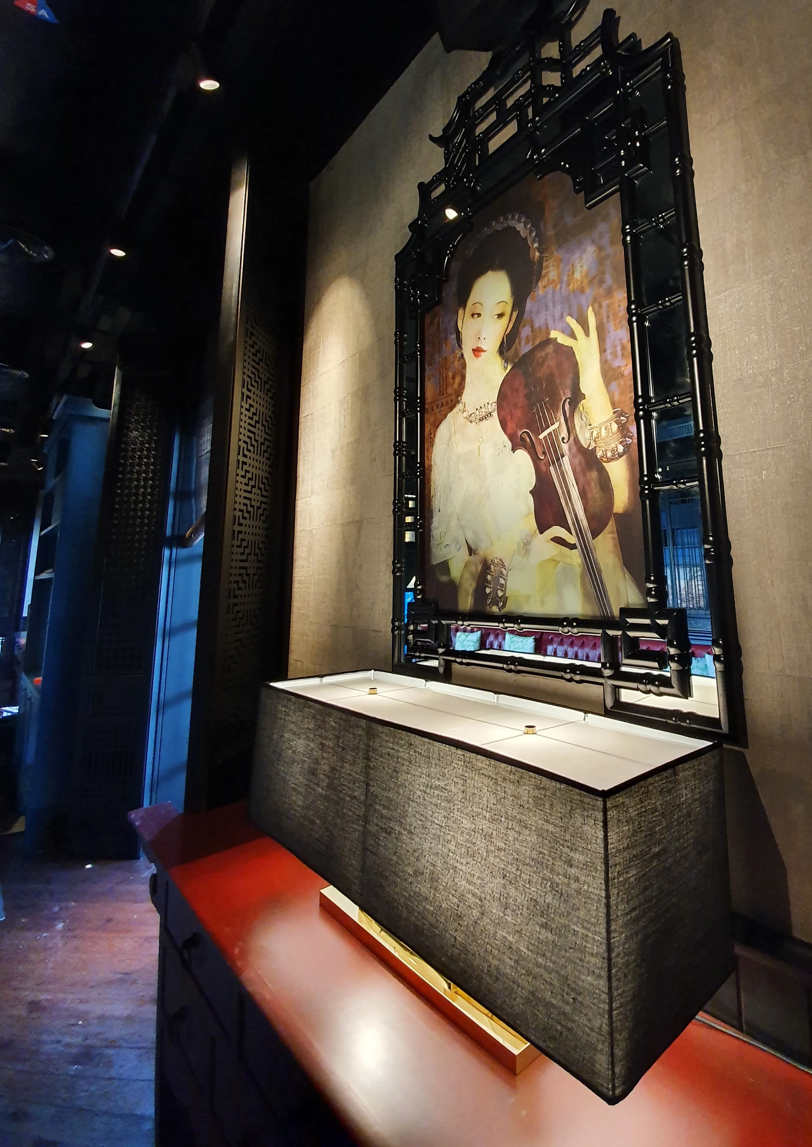 Interior photograph of a luxury Chinese restaurant, showing custom cultural fusion art. The artwork sits inside a black, classic Chinese pagoda mirror. The art is inspired by Chinese culture and 18th-century European art. With a woman holding a violin. 