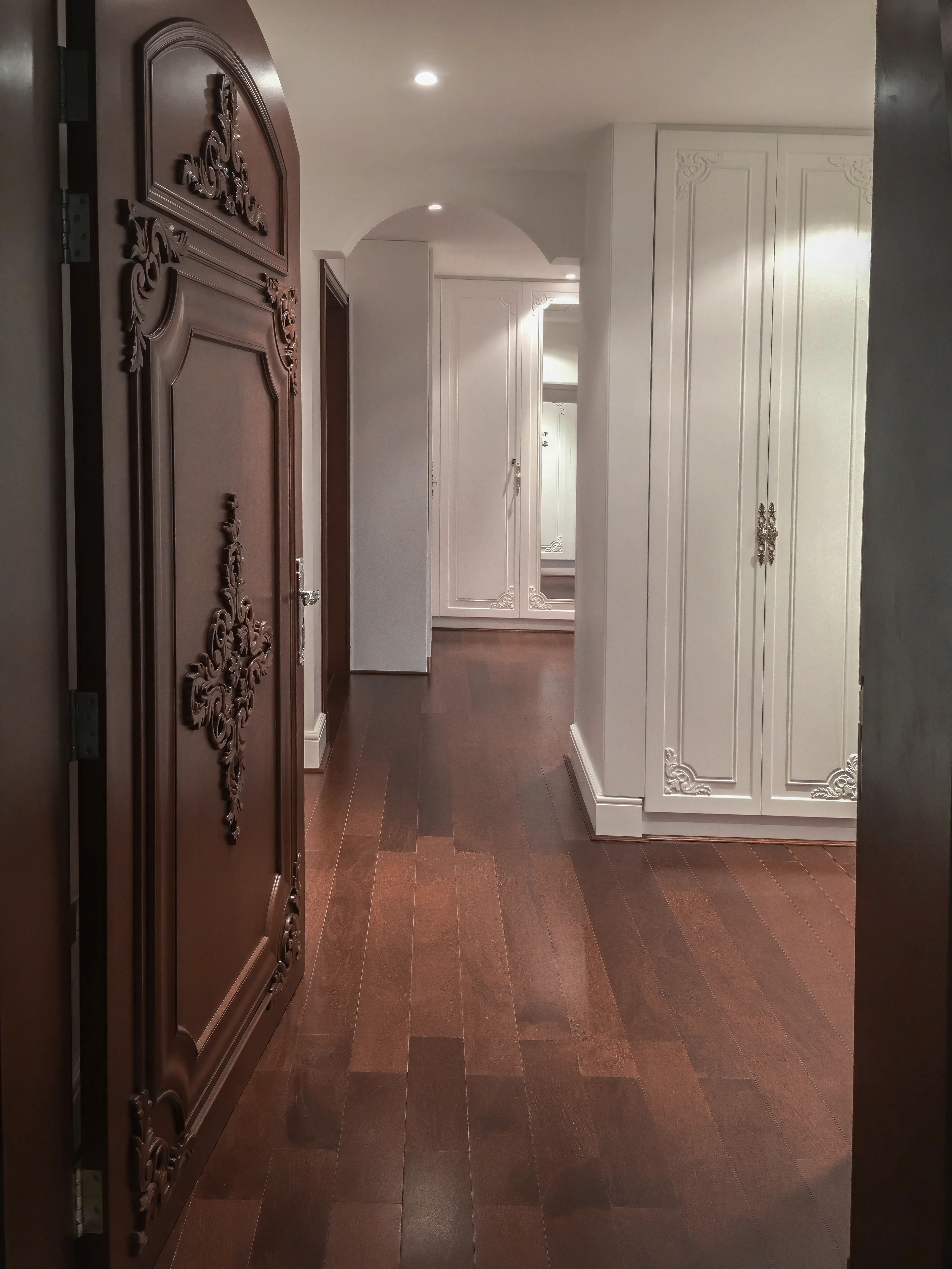 Custom mahogany wood bedroom door with carving. Dark mahogany floor and white closet with gold details.