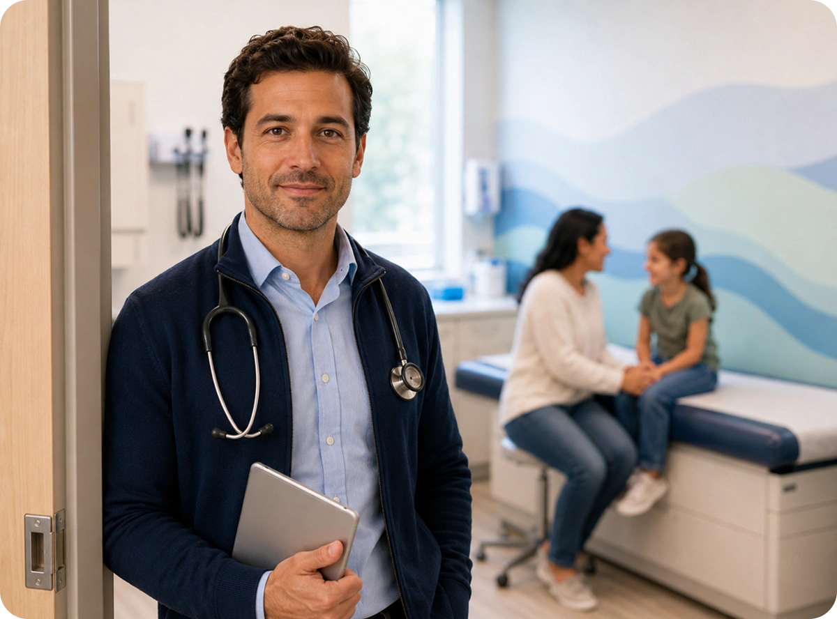 A doctor looks into the camera. A mother and a daughter are talking in the background hapily