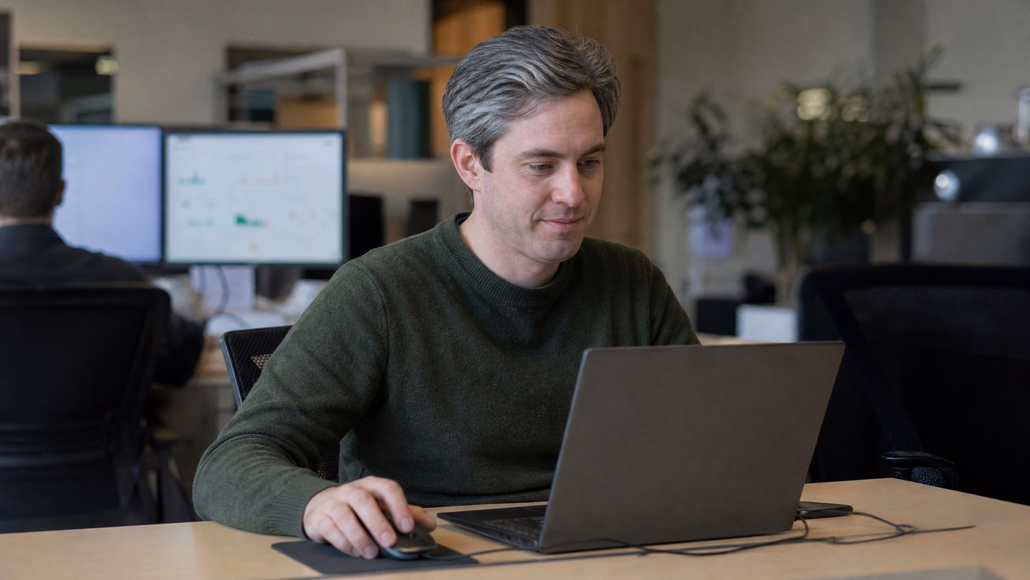 Man focusing on laptop, hand on mousepad