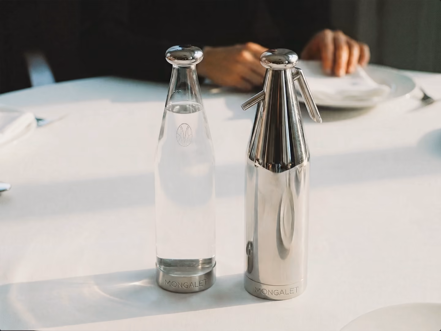 Carafe en verre et bouteille Mongalet sur une nappe blanche