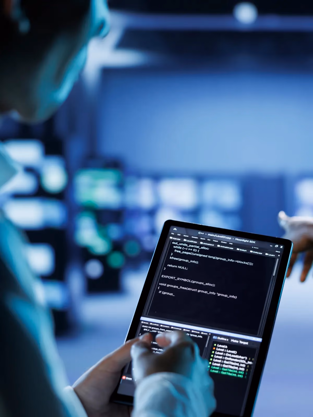 Engineer reviewing C source code on a tablet in a server room