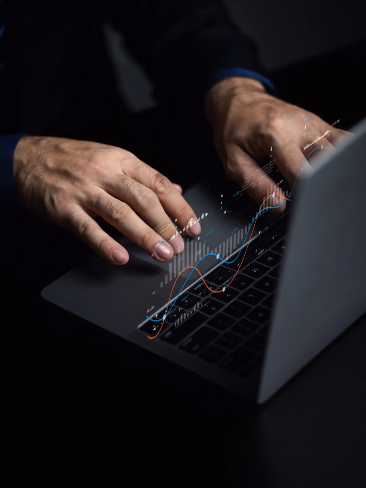 Hands typing on a laptop with data charts overlaid on the keyboard