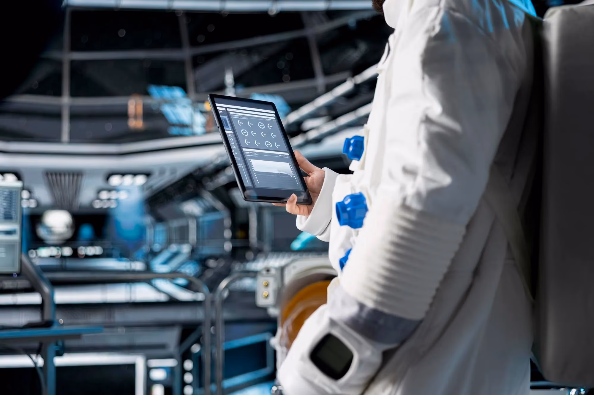Technician in a cleanroom suit operating a tablet control interface