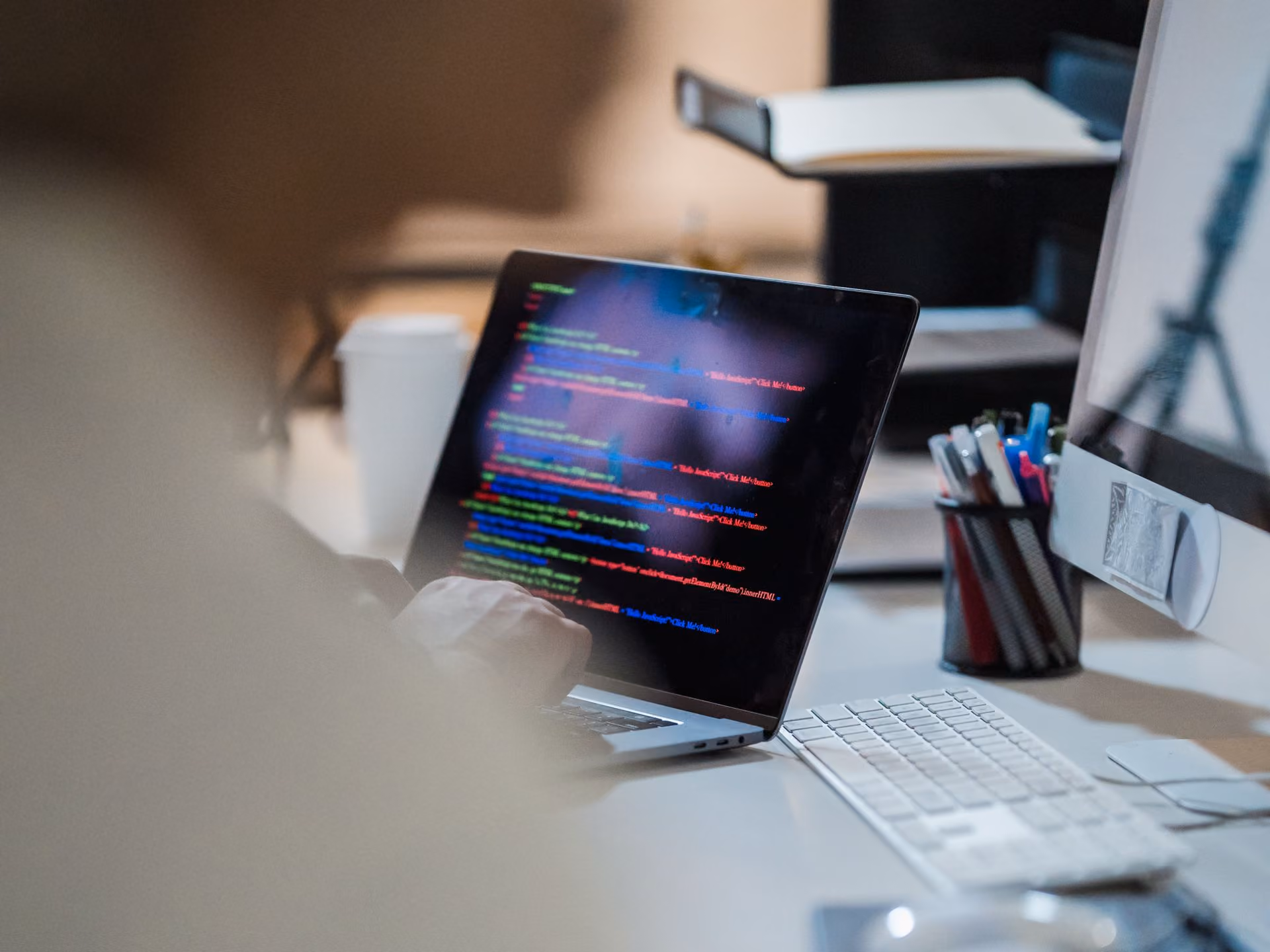 Developer writing code on a laptop at an office desk