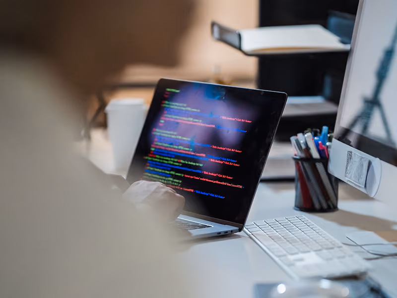 Developer writing code on a laptop at an office desk